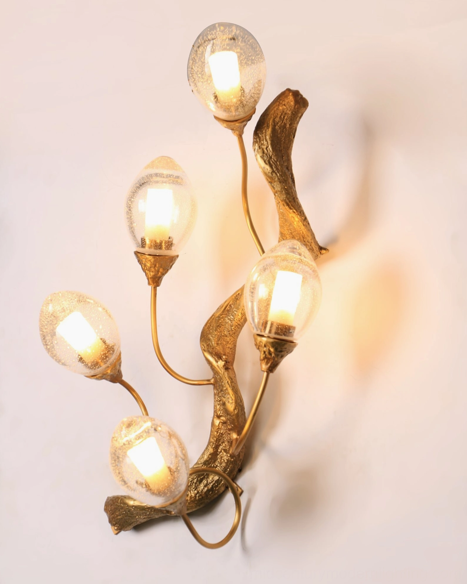 Lotus brass wall lamp close-up showing curved metal branches and exposed warm light bulbs