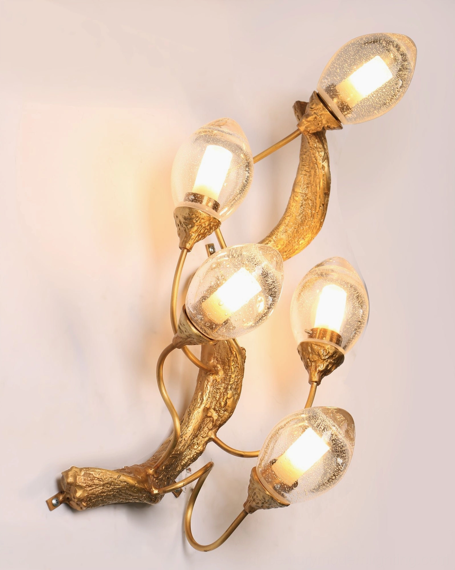 Lotus brass wall lamp with bubble-infused clear glass creating light diffusion effect