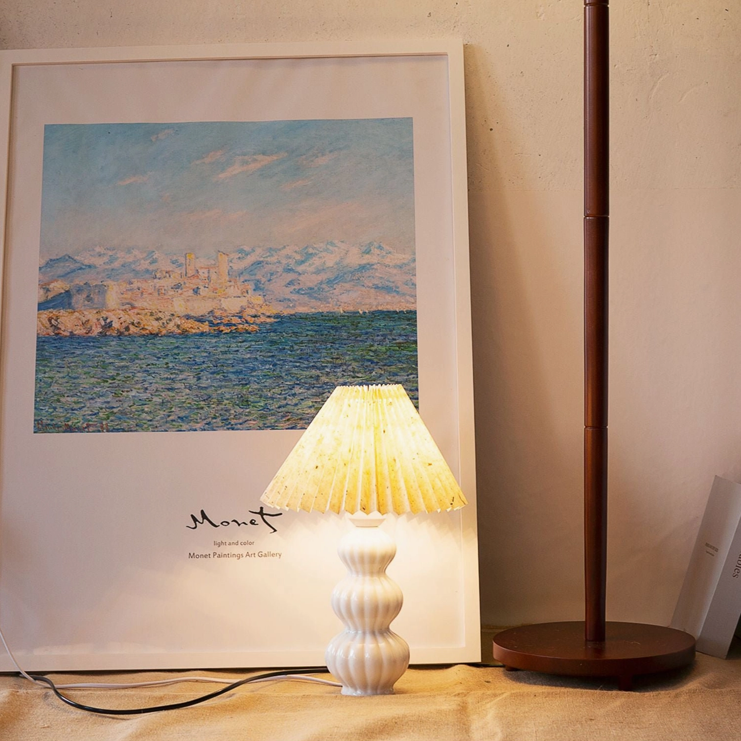 Luna pleated table lamp on desktop with art print backdrop, off-white pleated shade, cozy cottagecore home decor styling