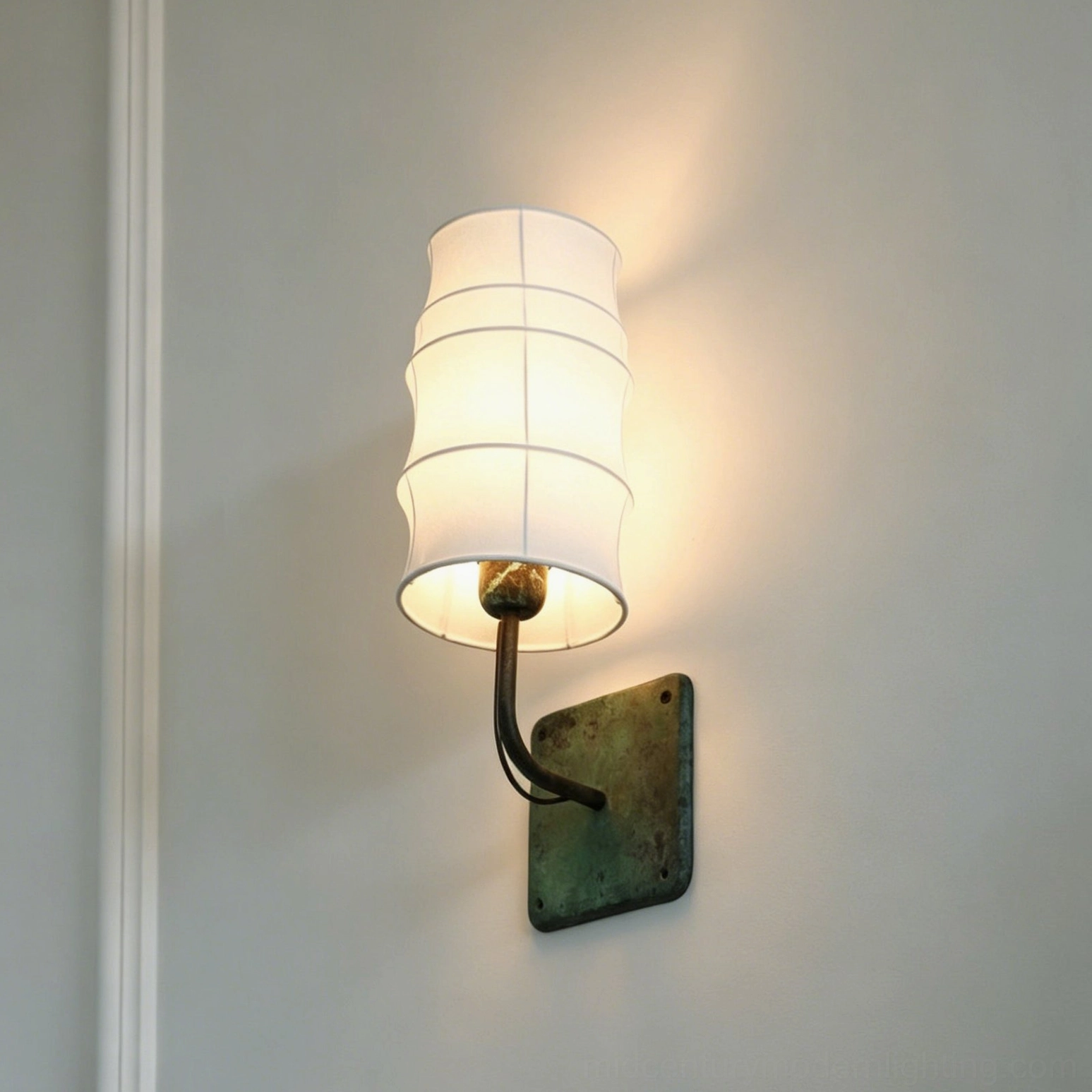 Maeve Lantern Wall Sconce with verdigris finish and tiered fabric shade creating soft glow on gray wall