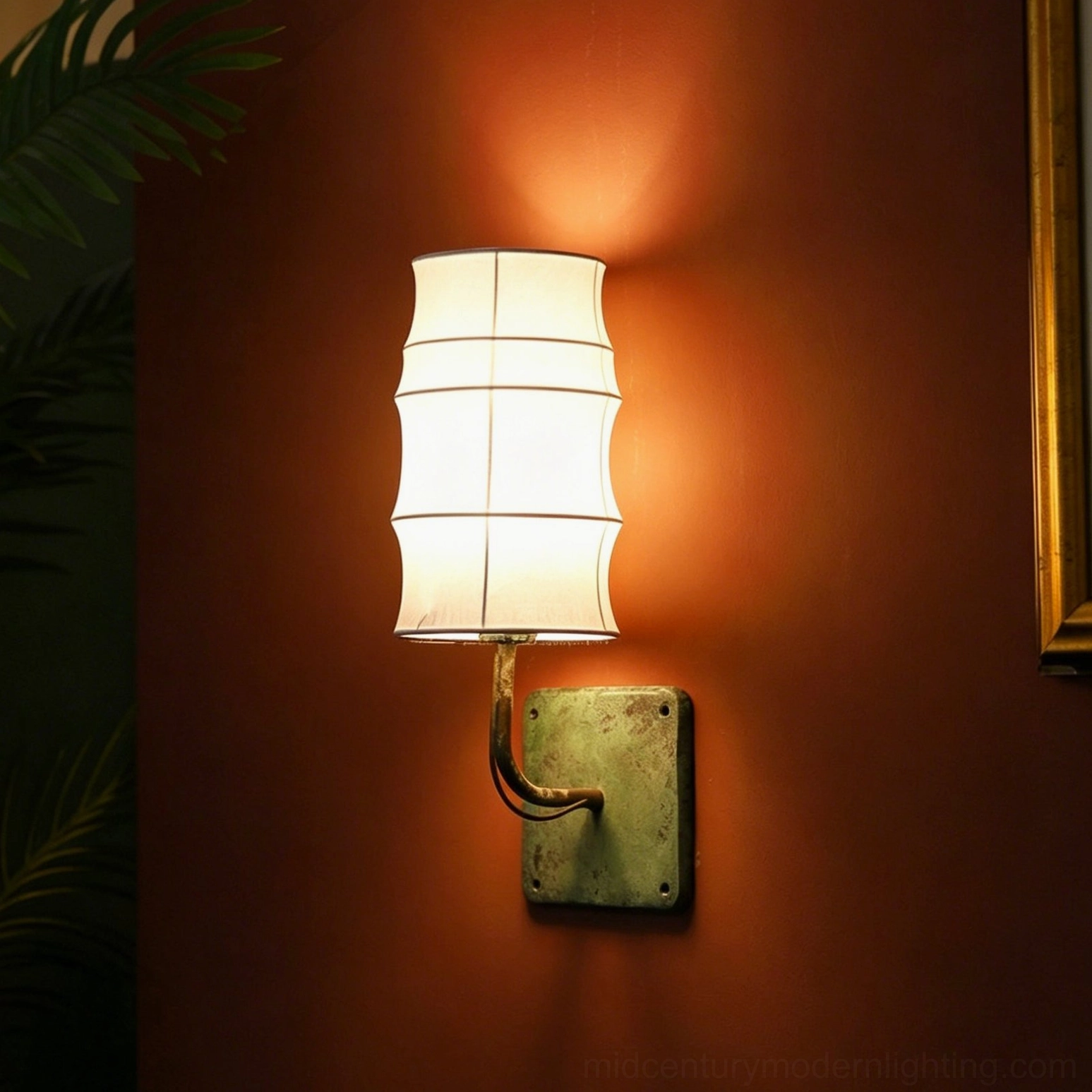 Maeve wall sconce with verdigris hardware and off-white tiered shade creating soft ambient light on terracotta wall