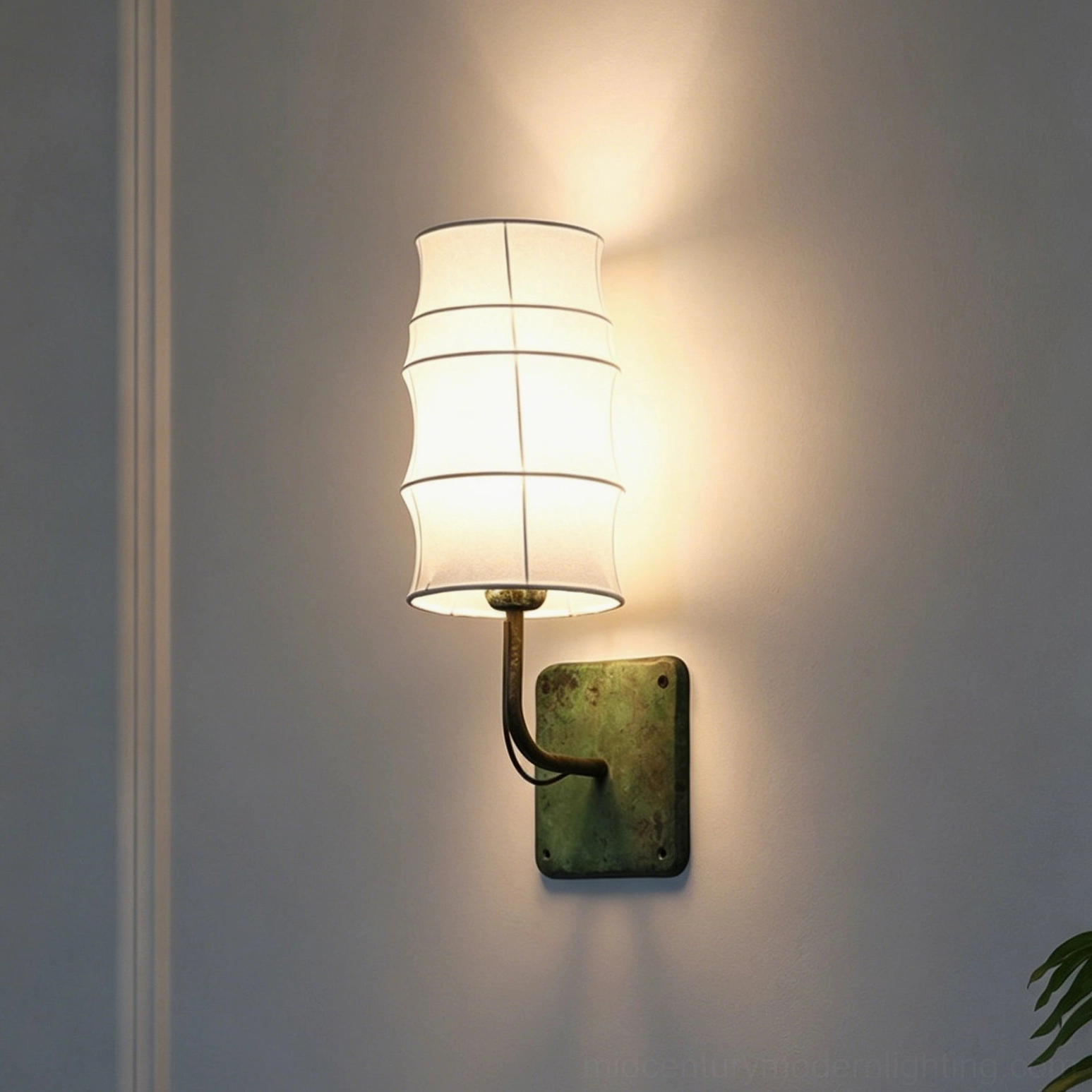 Three-quarter view of Maeve Wall Sconce showing verdigris metal base curved arm and off-white tiered shade