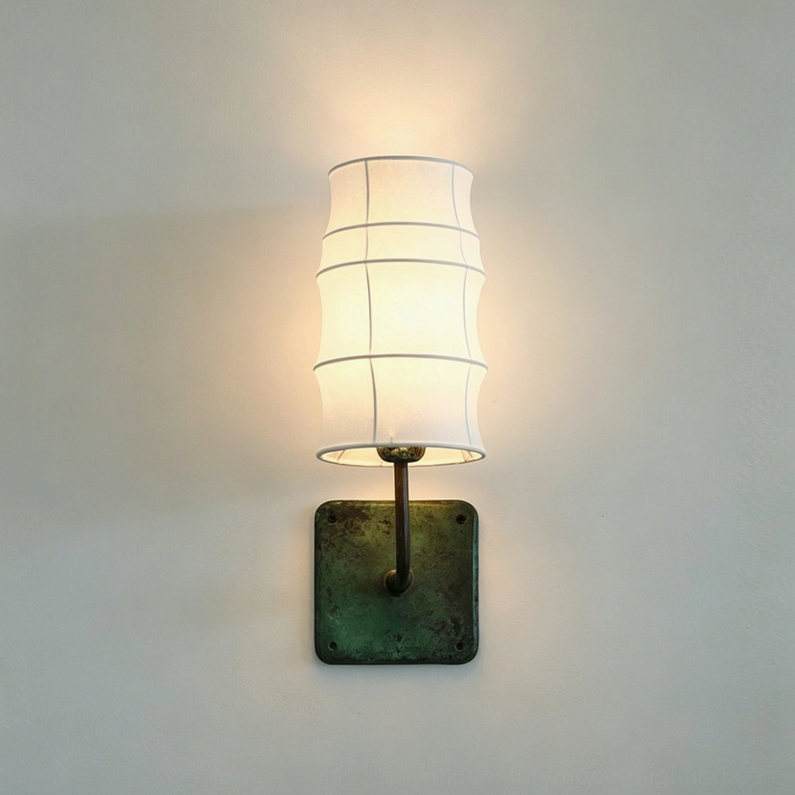 Wall-mounted Maeve Lantern Sconce with verdigris square base and tiered fabric shade against neutral gray backdrop