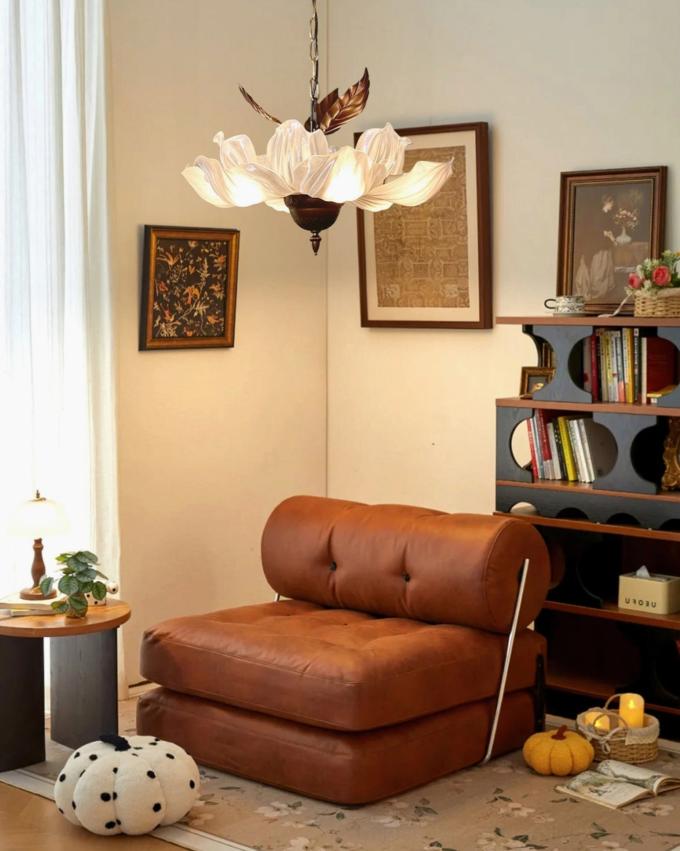 Magnolia Bloom Chandelier above reading nook with brown leather sofa and bookshelf decor
