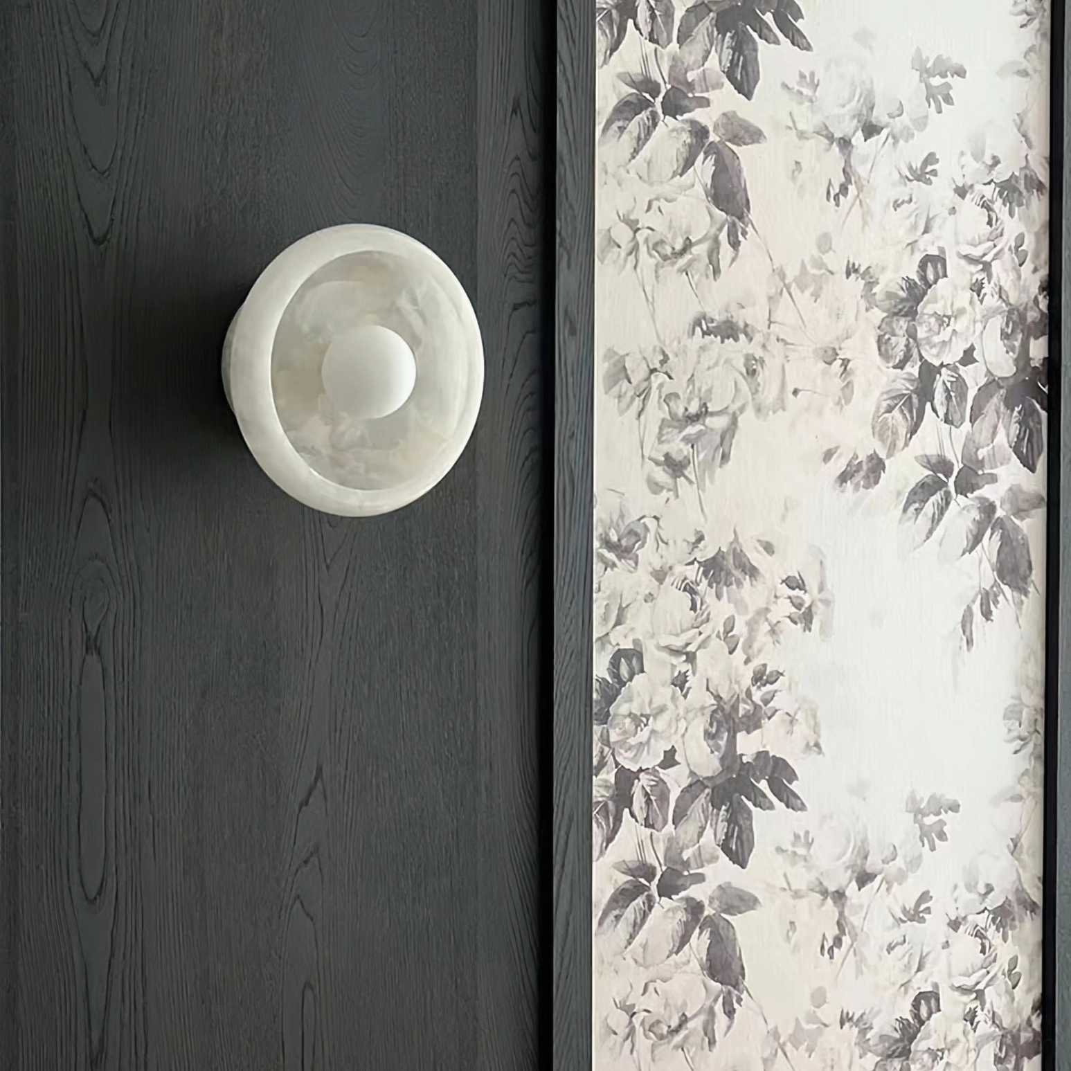 Minimalist marble wall lamp milky white stone, compact silhouette side front view with floral wall decor background