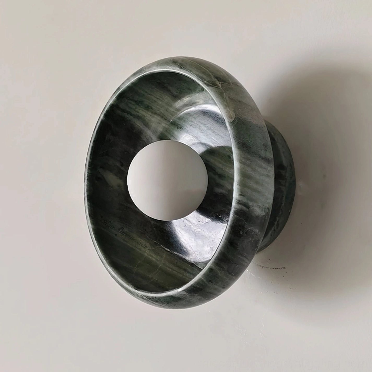 Marble wall lamp side three-quarter view showing ring-shaped hollow design, central bulb placement, natural stone craftsmanship