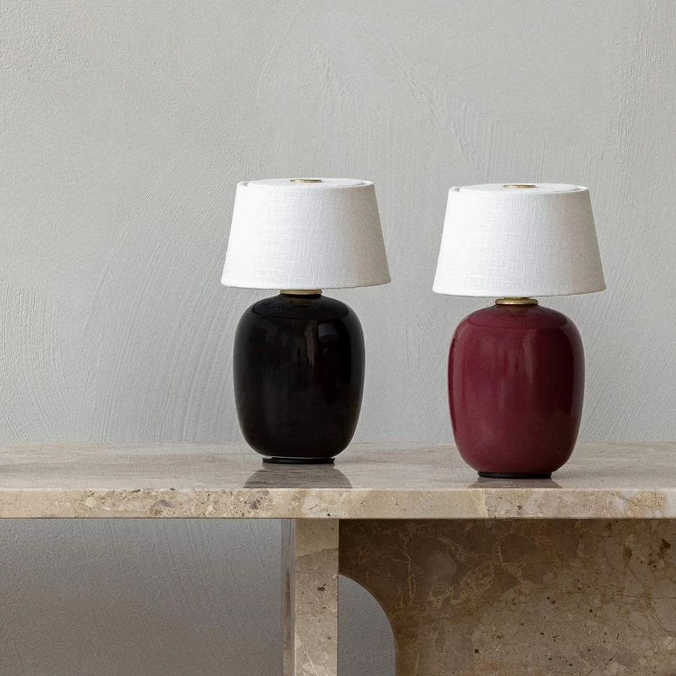 Two Marie table lamps black and red ceramic bases with white fabric shades on marble surface