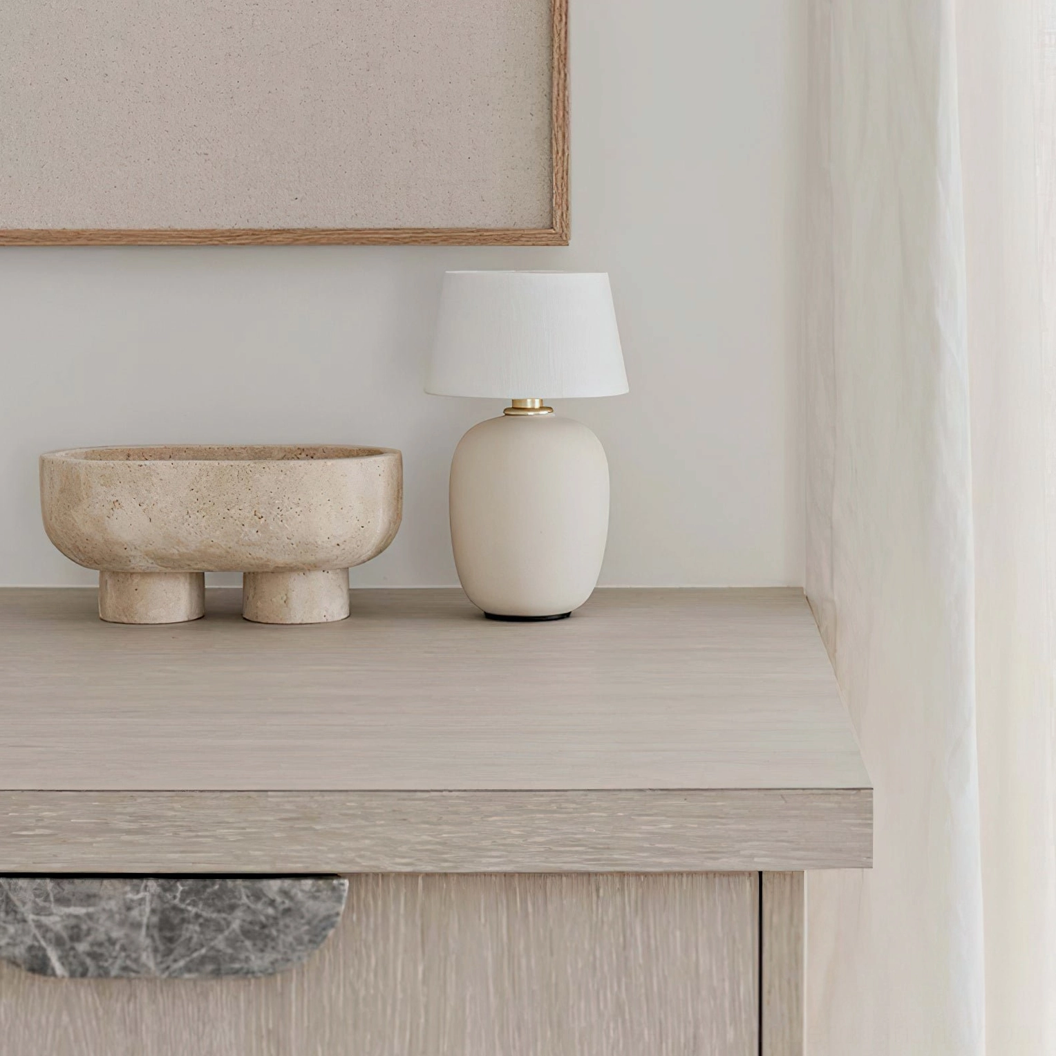 Beige ceramic Marie table lamp on entryway console table with travertine decorative bowl