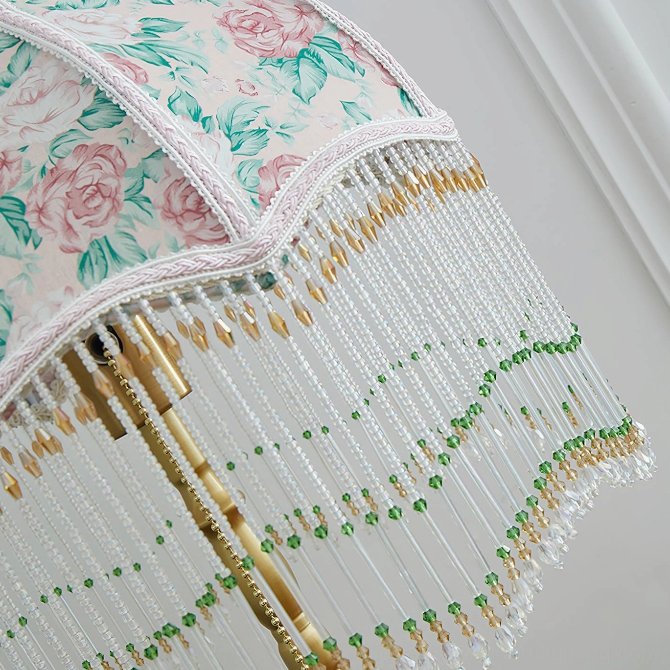 Masa lamp shade close-up showing pink rose fabric with braided trim and green beaded fringe detail