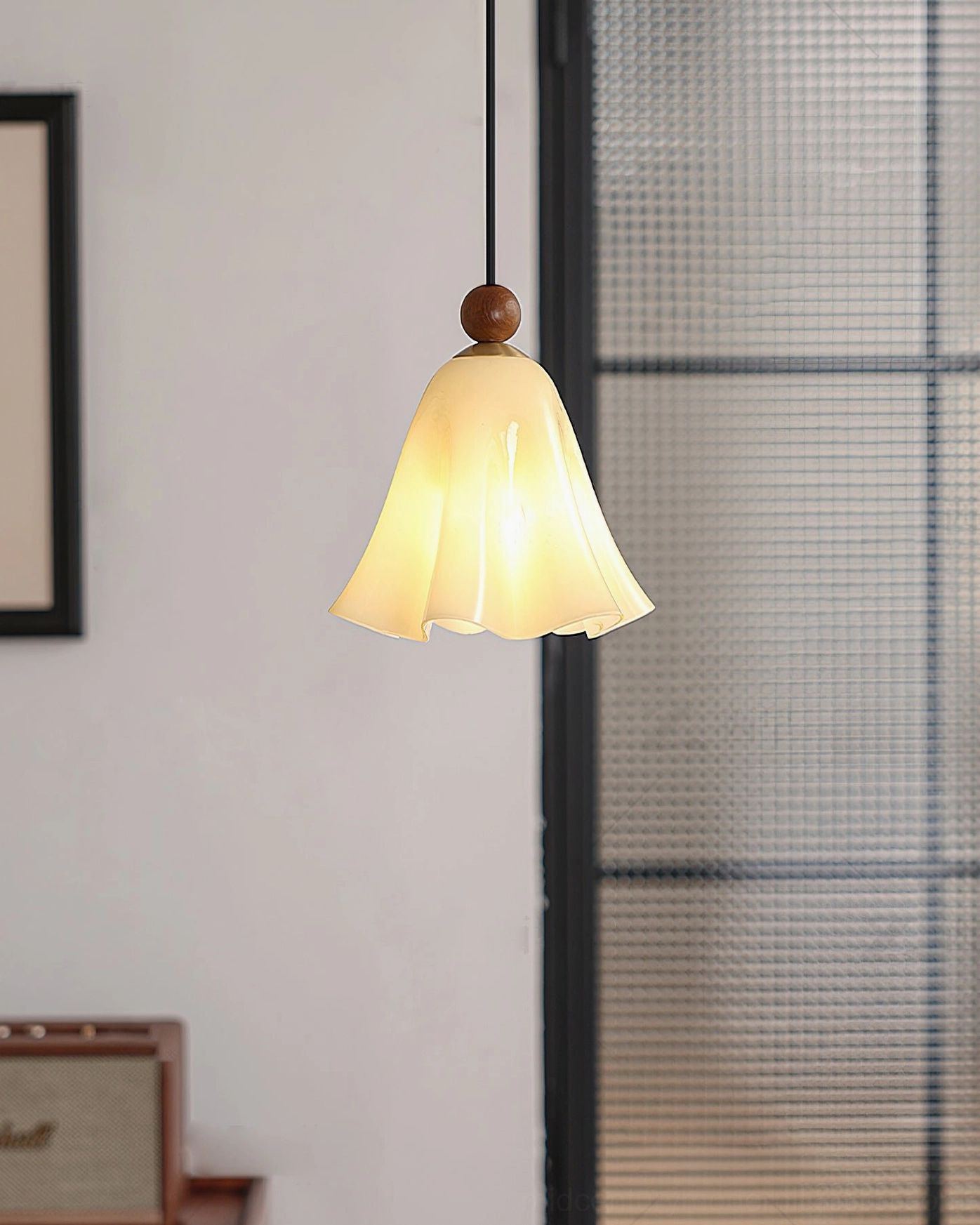Cream Meblo pendant light illuminated against grid glass partition with warm light and minimalist wall decor