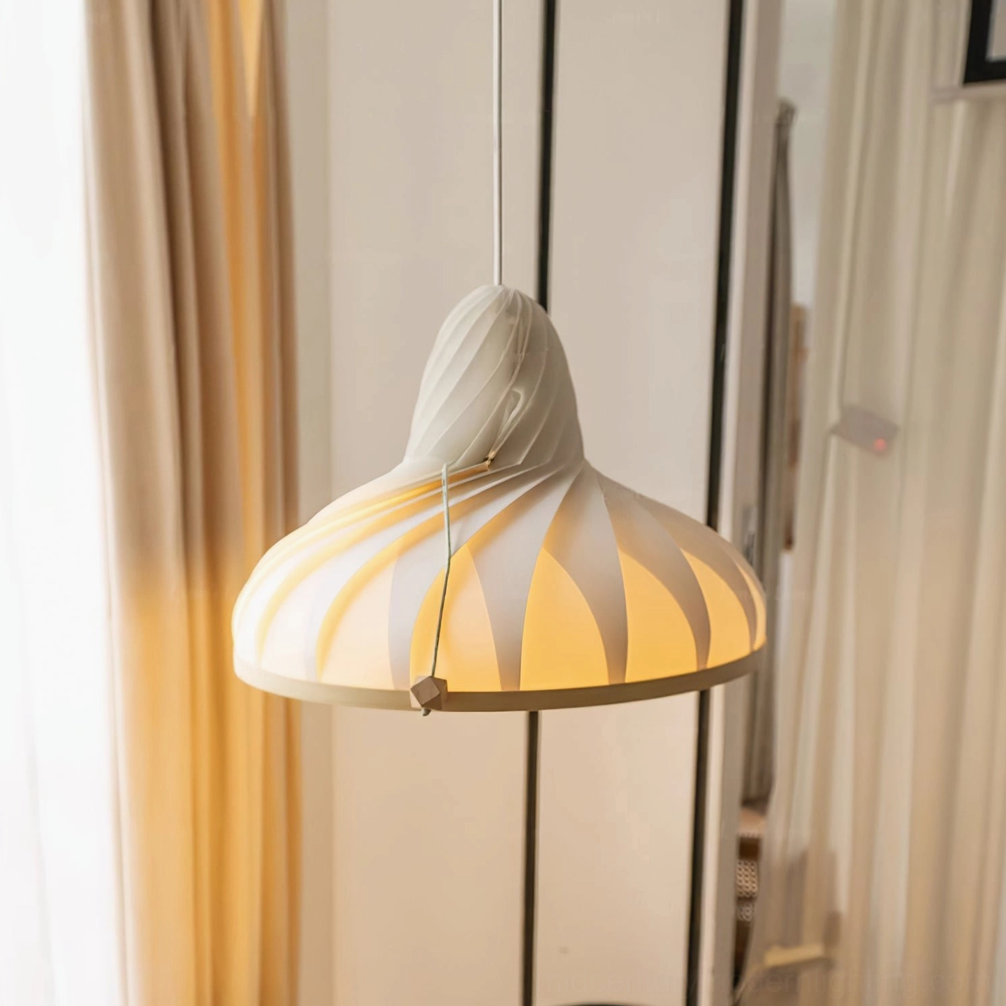 Meblo pendant lamp lit with warm yellow glow showing twisted fabric cord and beige interior styling