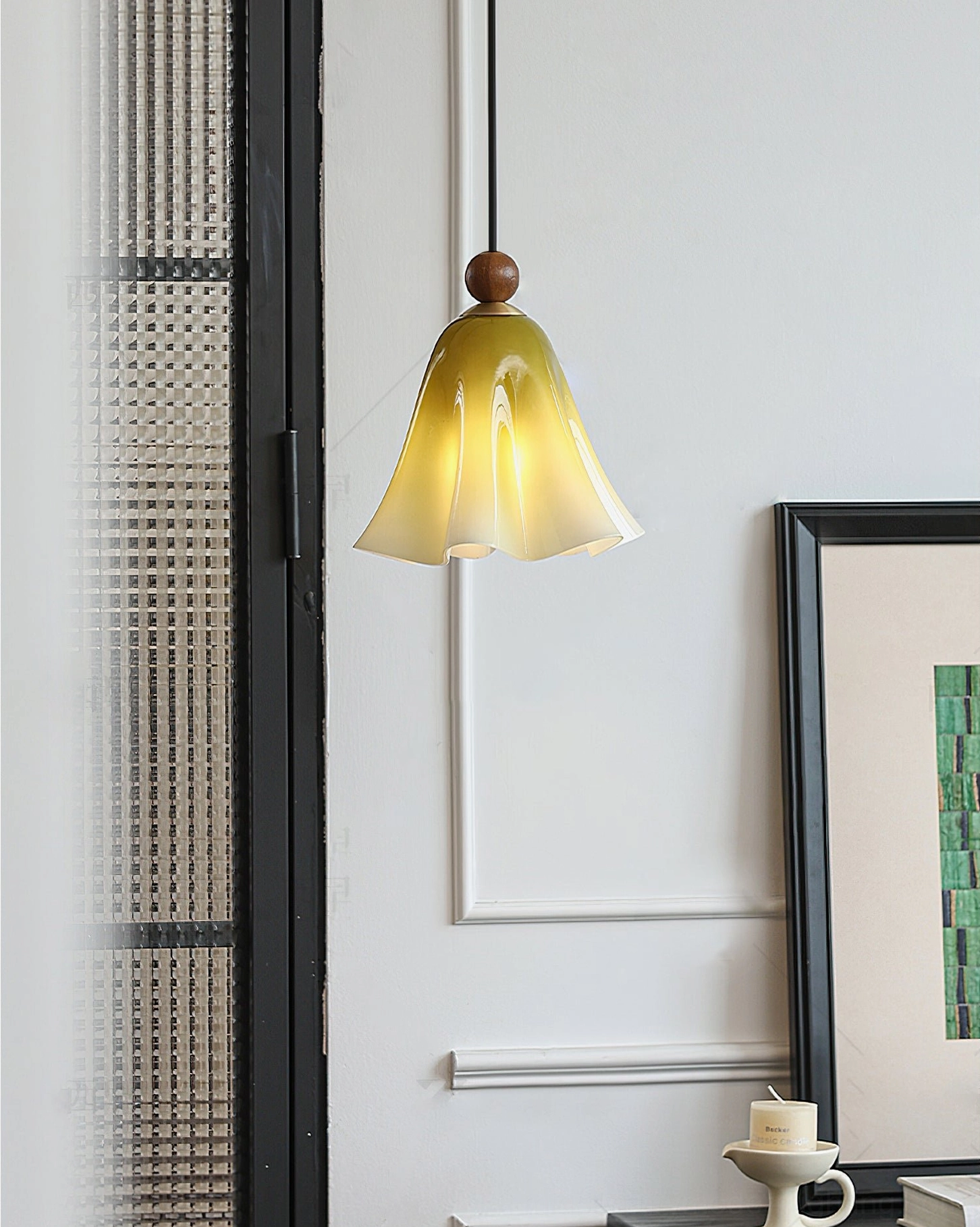 Yellow-green gradient Meblo pendant light near glass door with framed artwork and black hanging cord detail