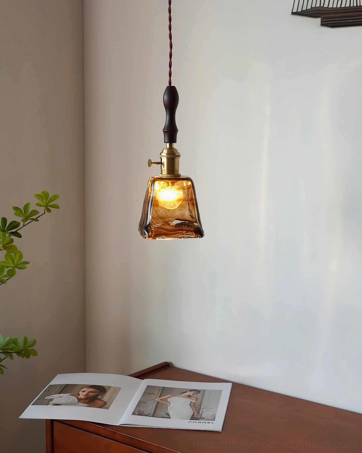 Mid-century modern amber glass pendant lamp showing sculptural glass and wood hardware craftsmanship detail