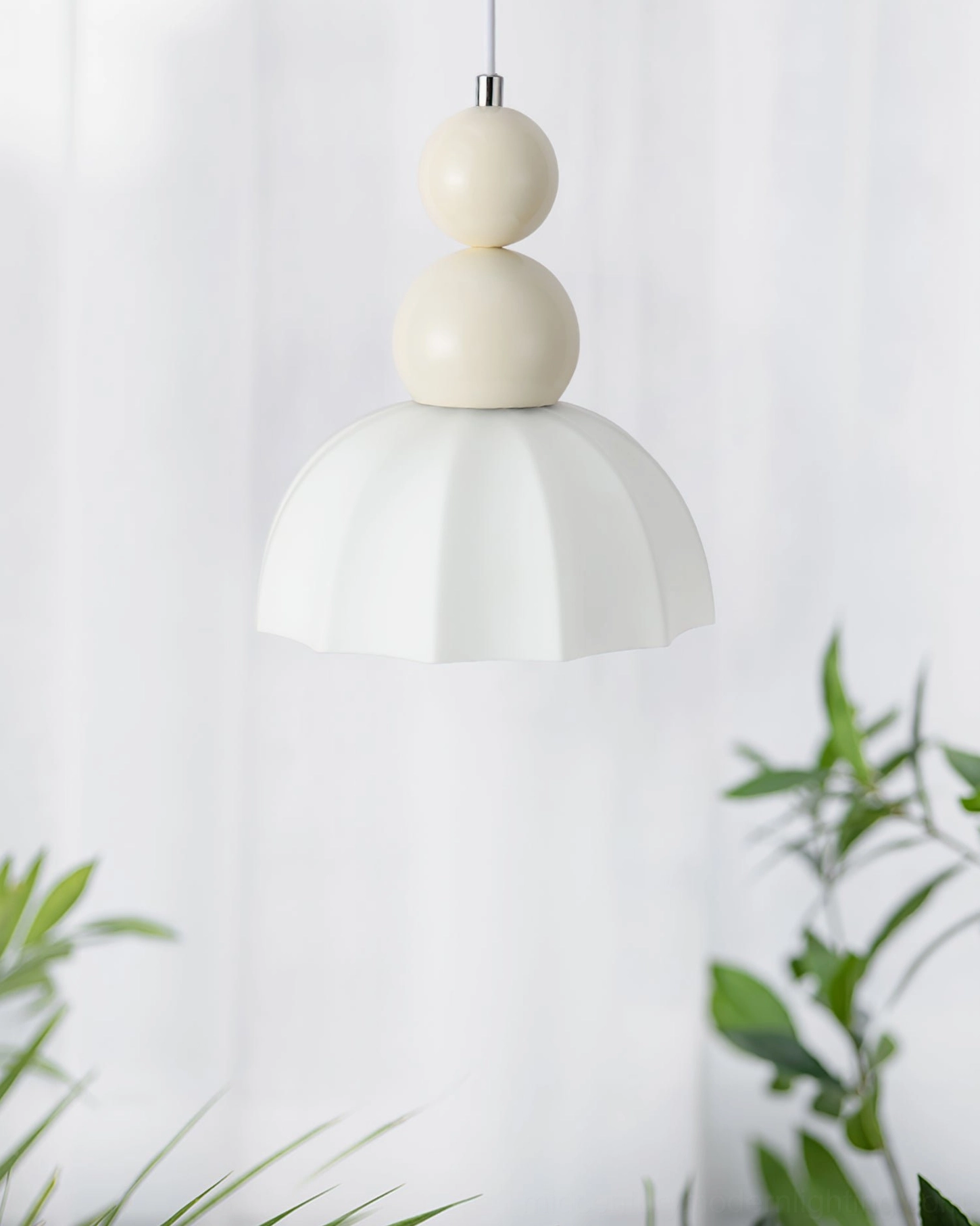 Mid-century modern bubble pendant light installed in minimalist bedroom with sheer curtains and green plants
