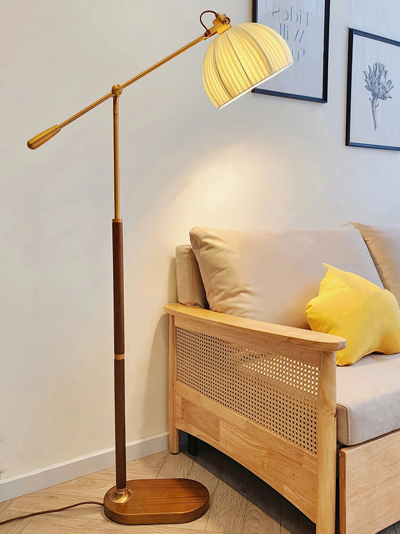 Mid-century modern floor lamp with warm yellow illuminated pleated shade and brass wood design in wooden frame sofa living room setting