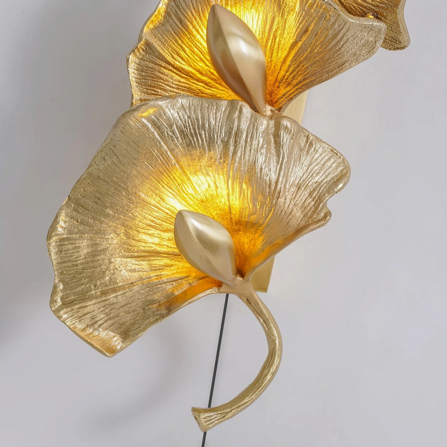 Golden ginkgo leaf wall lamp mounted in luxury modern home entryway with warm atmospheric lighting