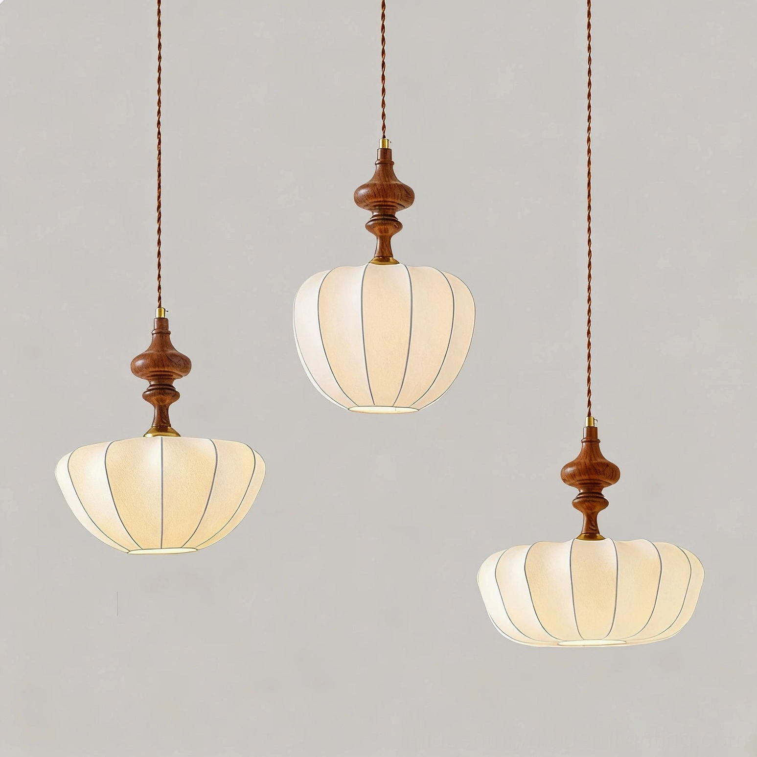 Set of three mid-century pendant lights with beige ribbed fabric shades and twisted brown cords, minimalist backdrop