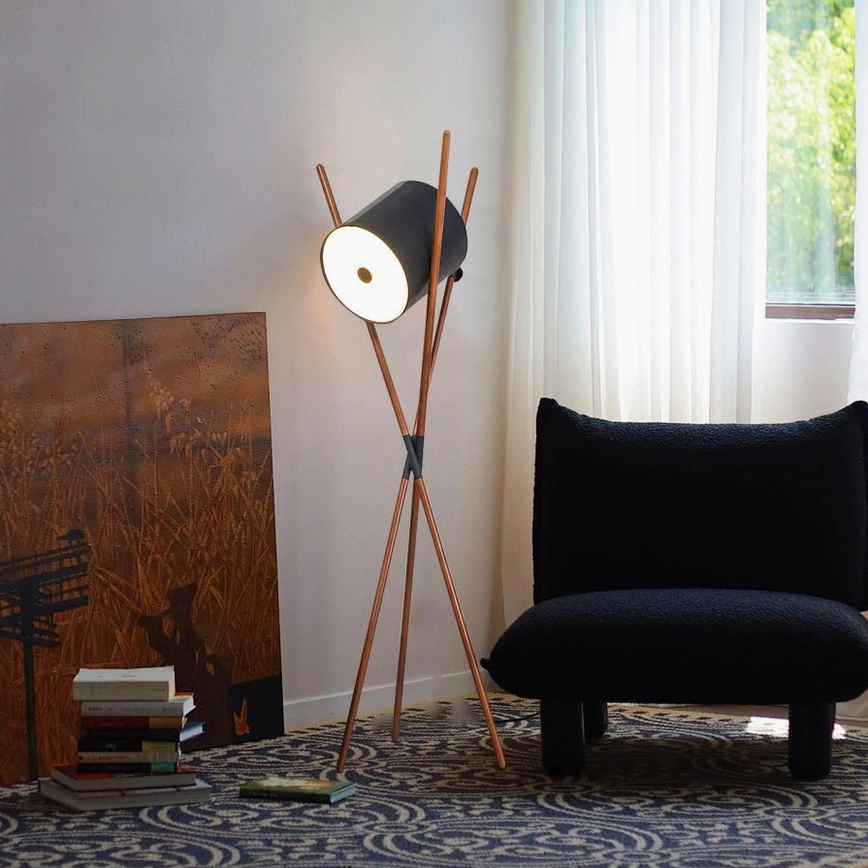 Mid-century modern floor lamp with natural wood tripod base and black shade in Scandinavian living room setting