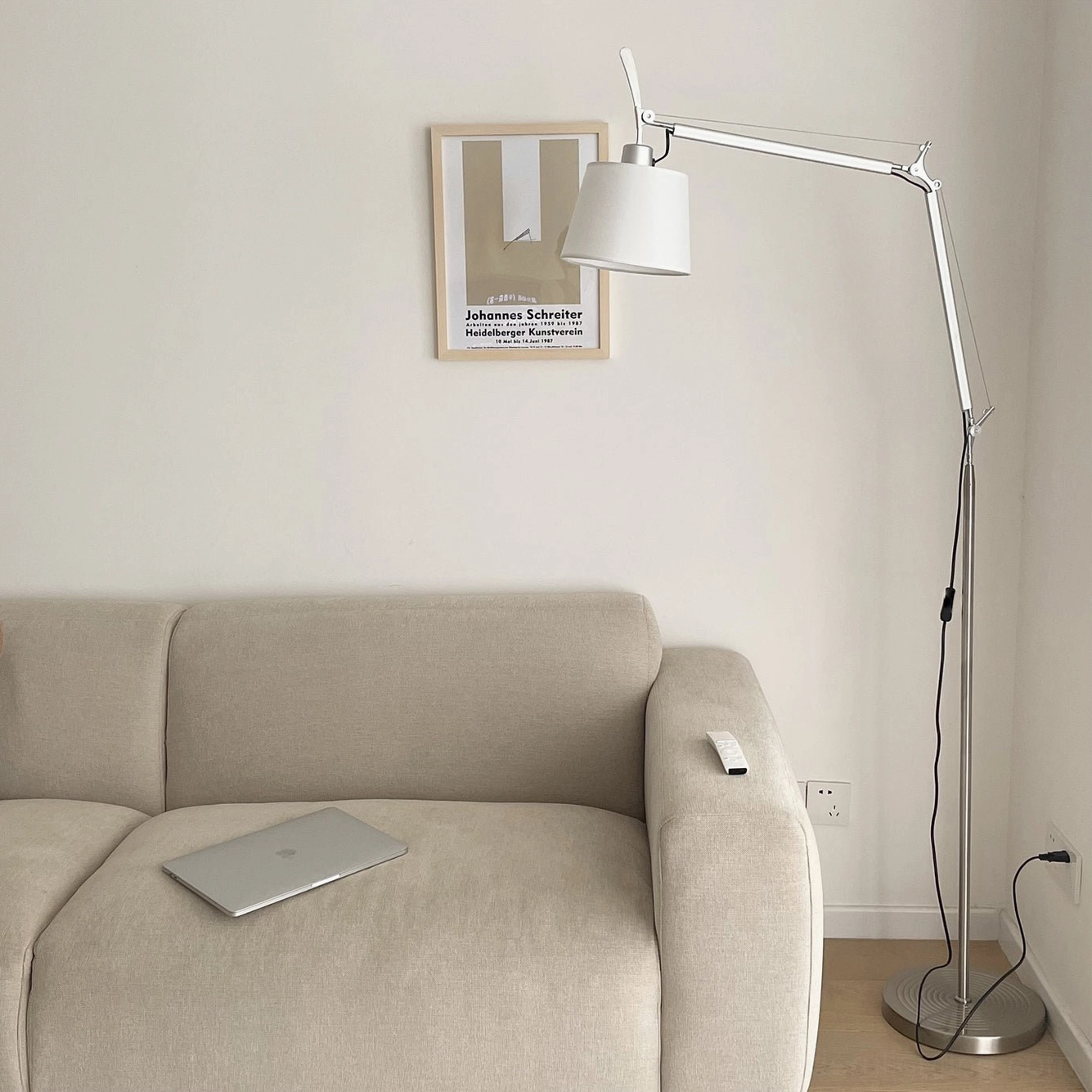 Mid-century swing arm floor lamp beside beige sofa in modern living room, compact silver metal arm design