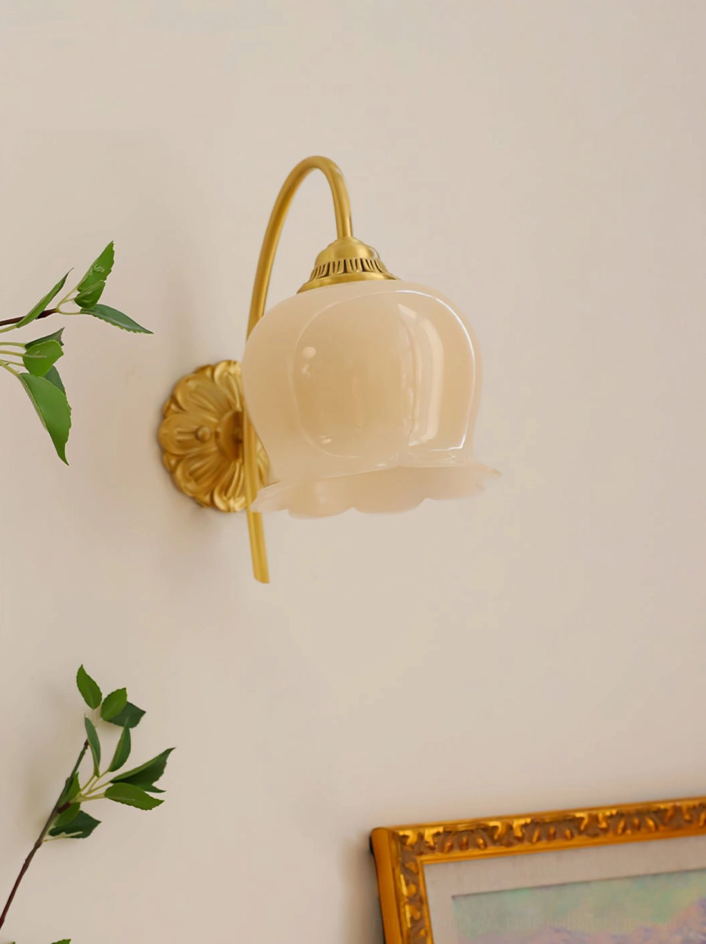 Low-angle view of floral shaped lily of the valley wall lamp with gold brass arms and flower shade
