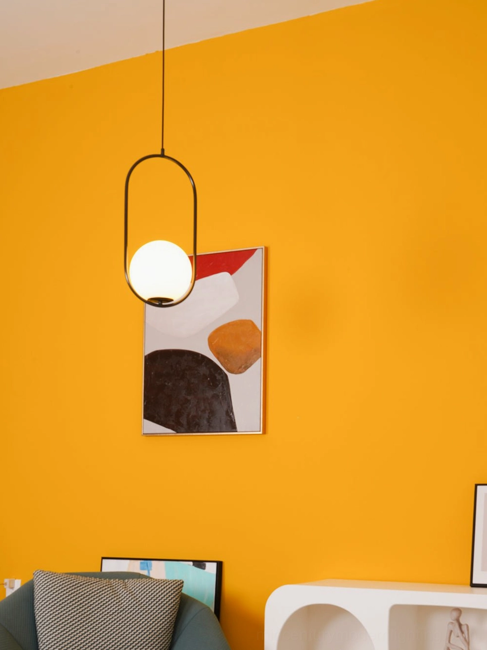Mila oval pendant light with black metal frame and frosted white glass shade in modern seating area with orange accent wall - minimalist hanging light