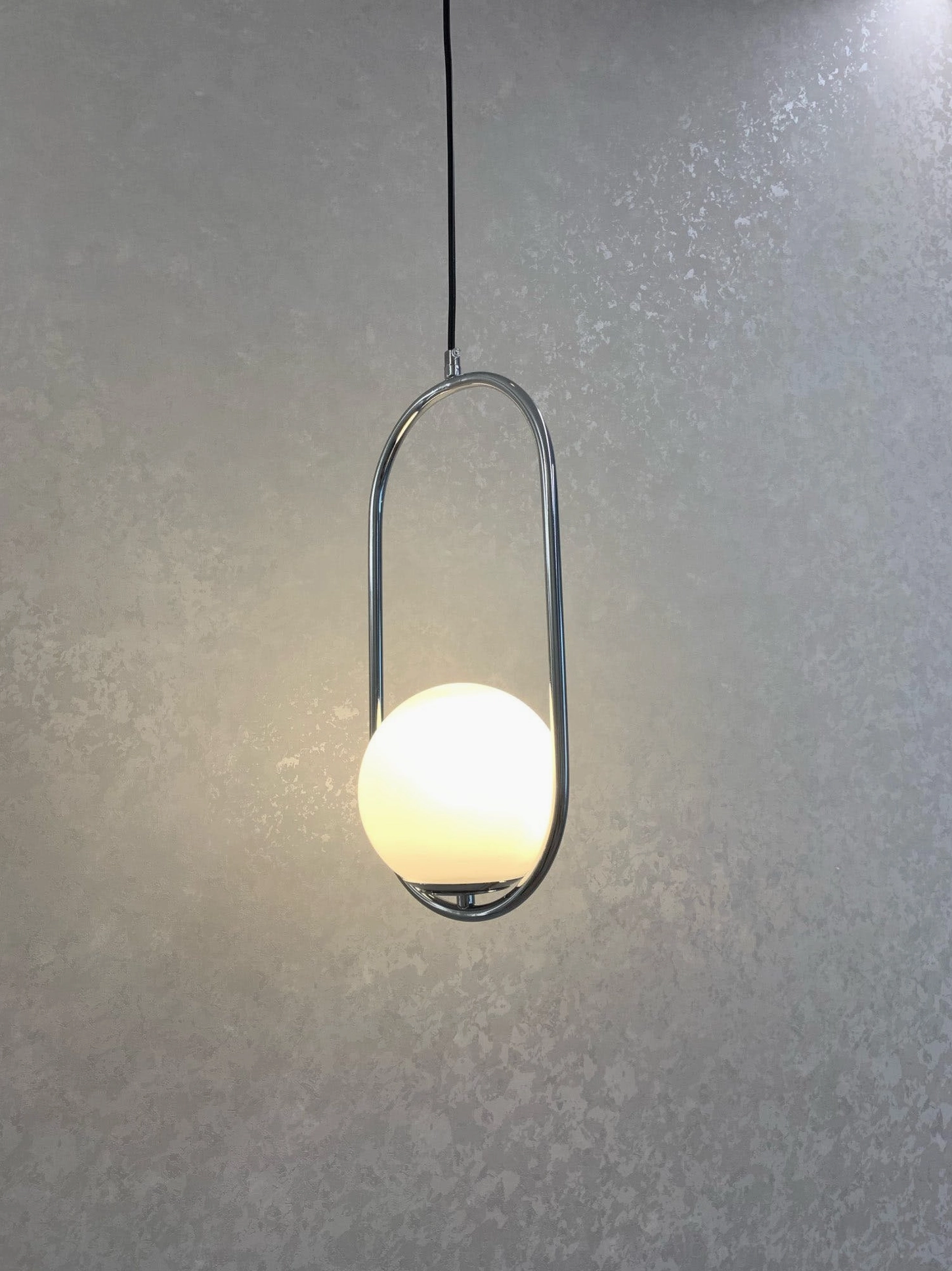 Mila minimalist pendant light with dark metal oval frame and frosted white glass shade front view on grey textured studio background