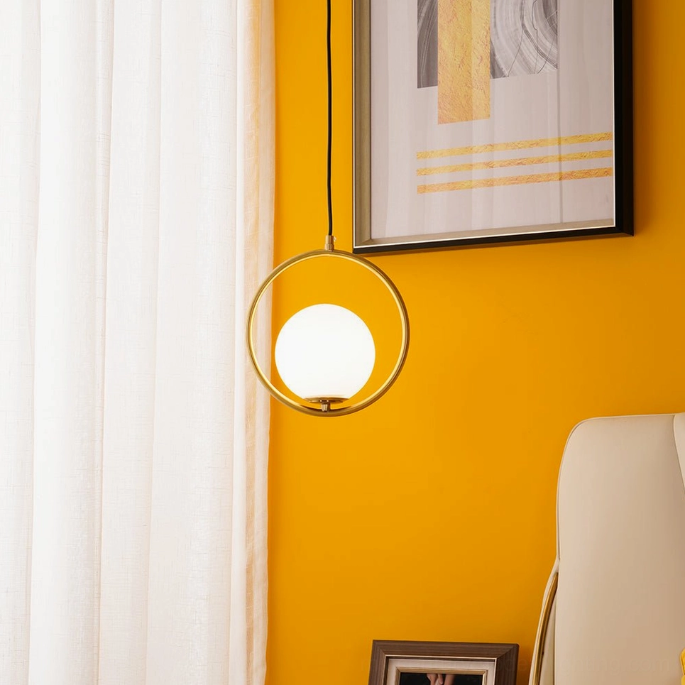 Mila geometric hoop pendant light in gold finish with warm glass globe shade in bedroom with orange accent wall - contemporary minimalist pendant