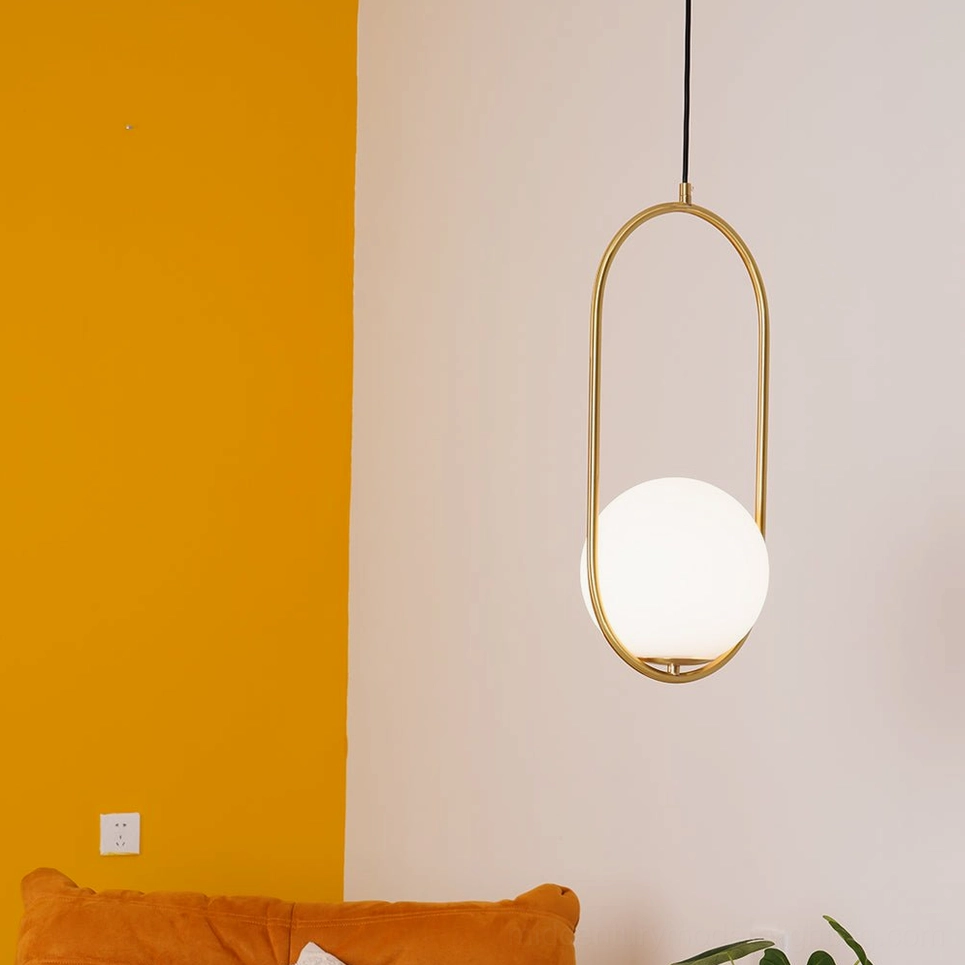 Mila oval pendant light with gold metal frame and frosted white glass shade in Nordic minimalist home lounge with two-tone wall and orange sofa