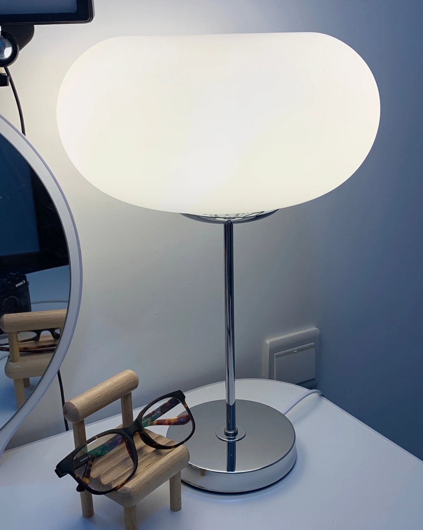 Contemporary frosted glass table lamp styled on vanity desk with modern minimalist aesthetic