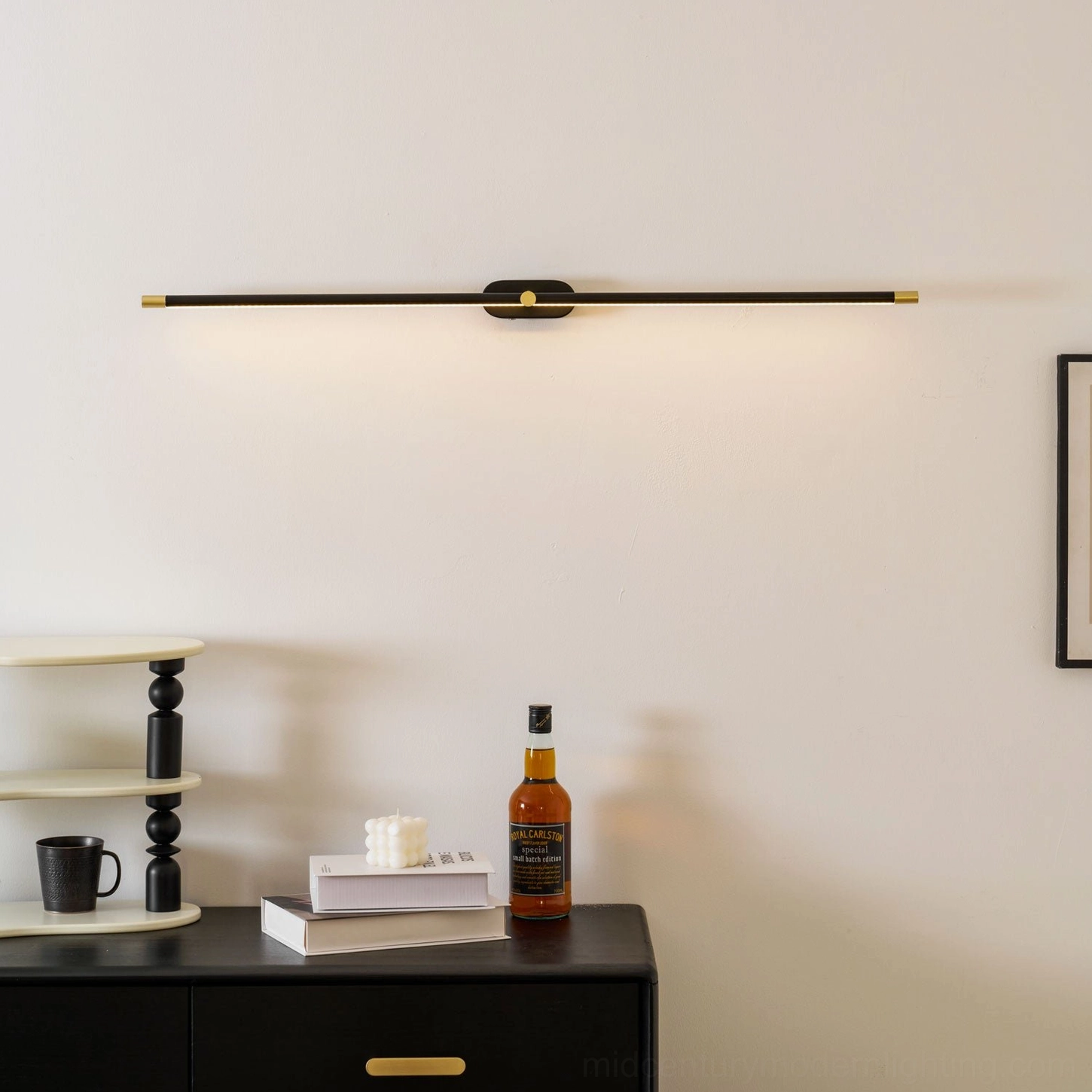 Minimalist wall lamp side profile view displayed on accent table with decorative bottles and books