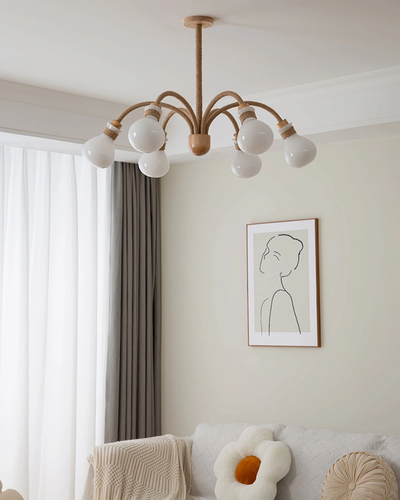6-light wooden rope chandelier with unlit white bulbs suspended above neutral fabric sofa in warm minimalist living room