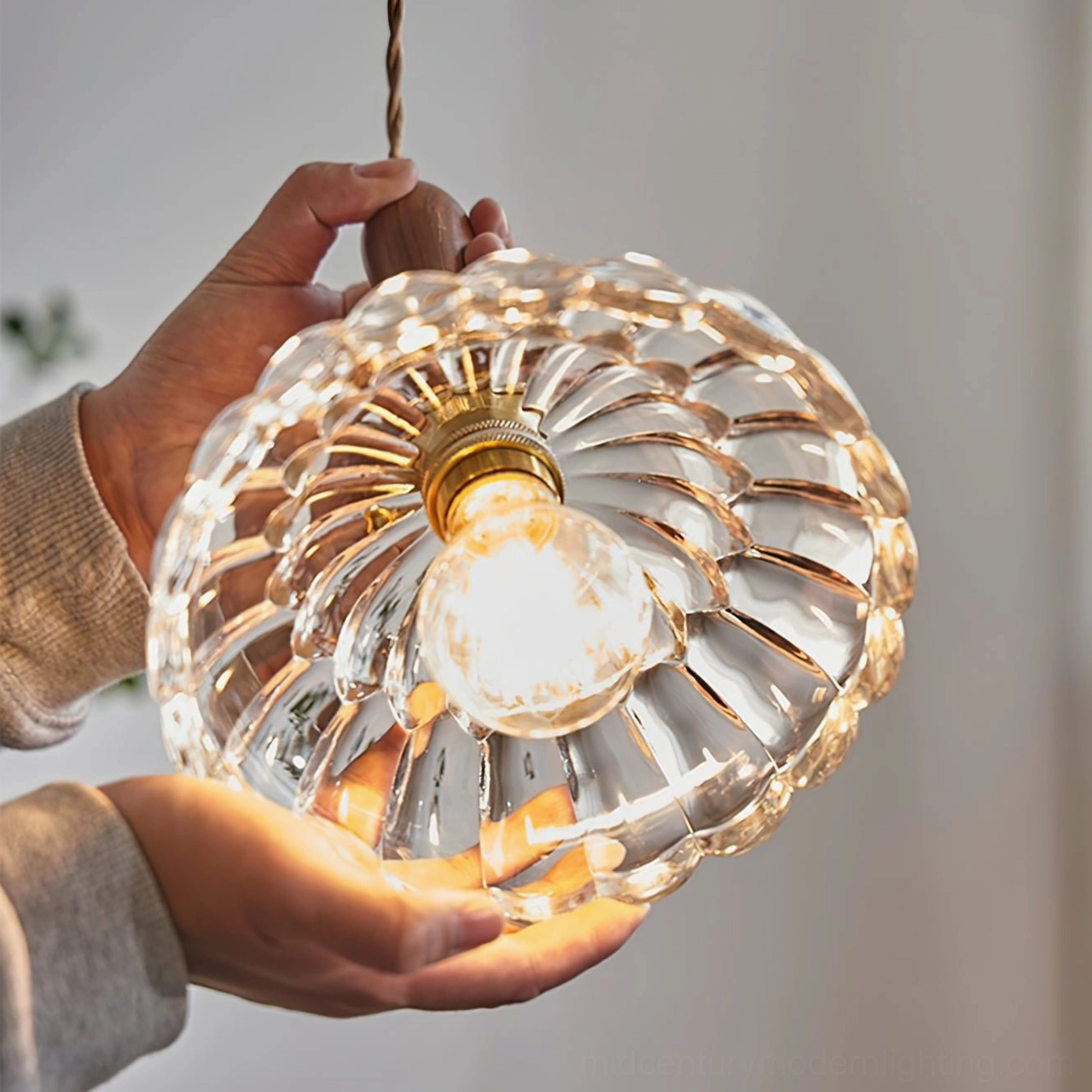 Close-up overhead view of clear ribbed glass pendant lamp shade with exposed bulb and wooden grip detail