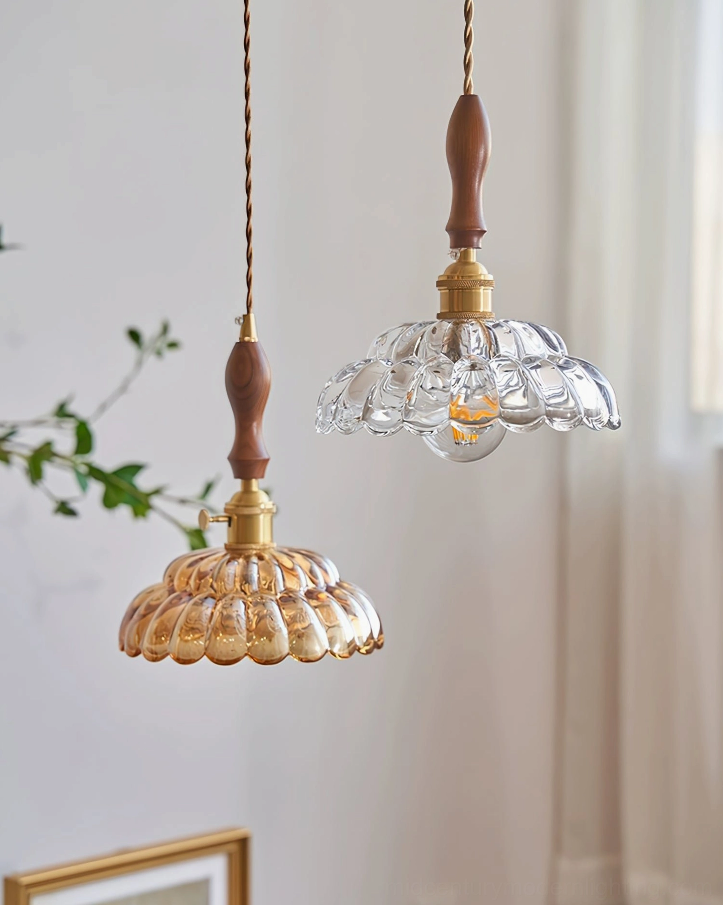 Two coordinated Misisco pendant lamps with clear and amber fluted glass hanging indoors with curtain and greenery