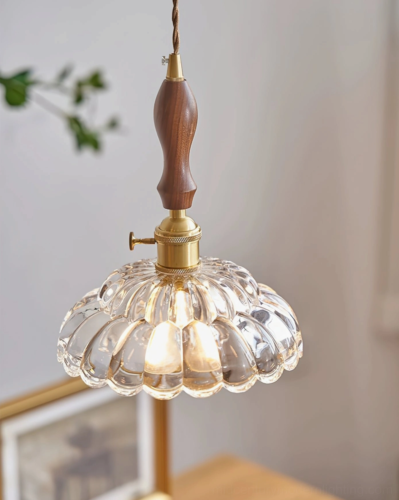 Lit clear fluted glass pendant lamp with warm Edison bulb, brass accents and wooden details in modern interior