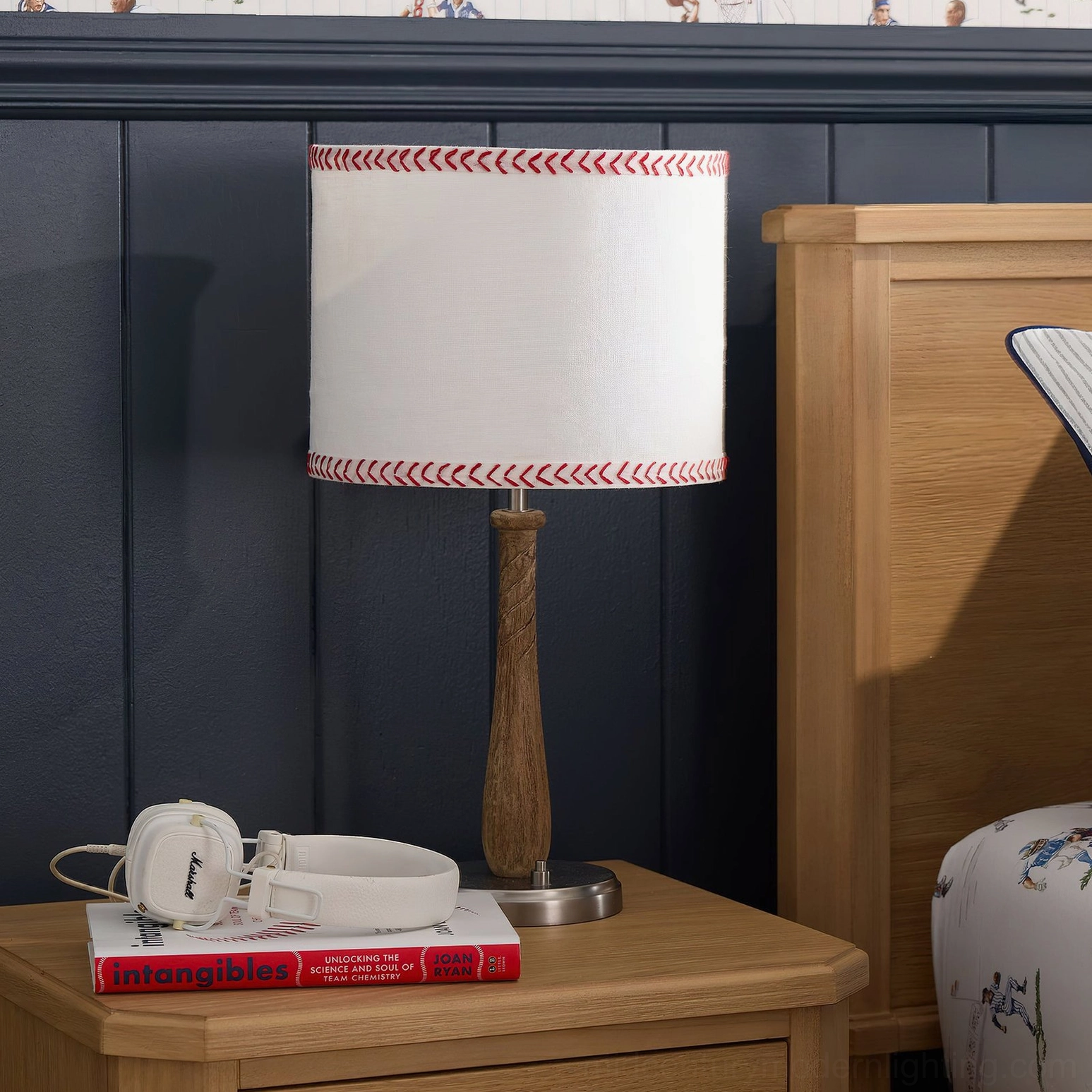 Mitchell baseball bat table lamp styled on wooden nightstand in modern bedroom with navy accent wall and stacked books