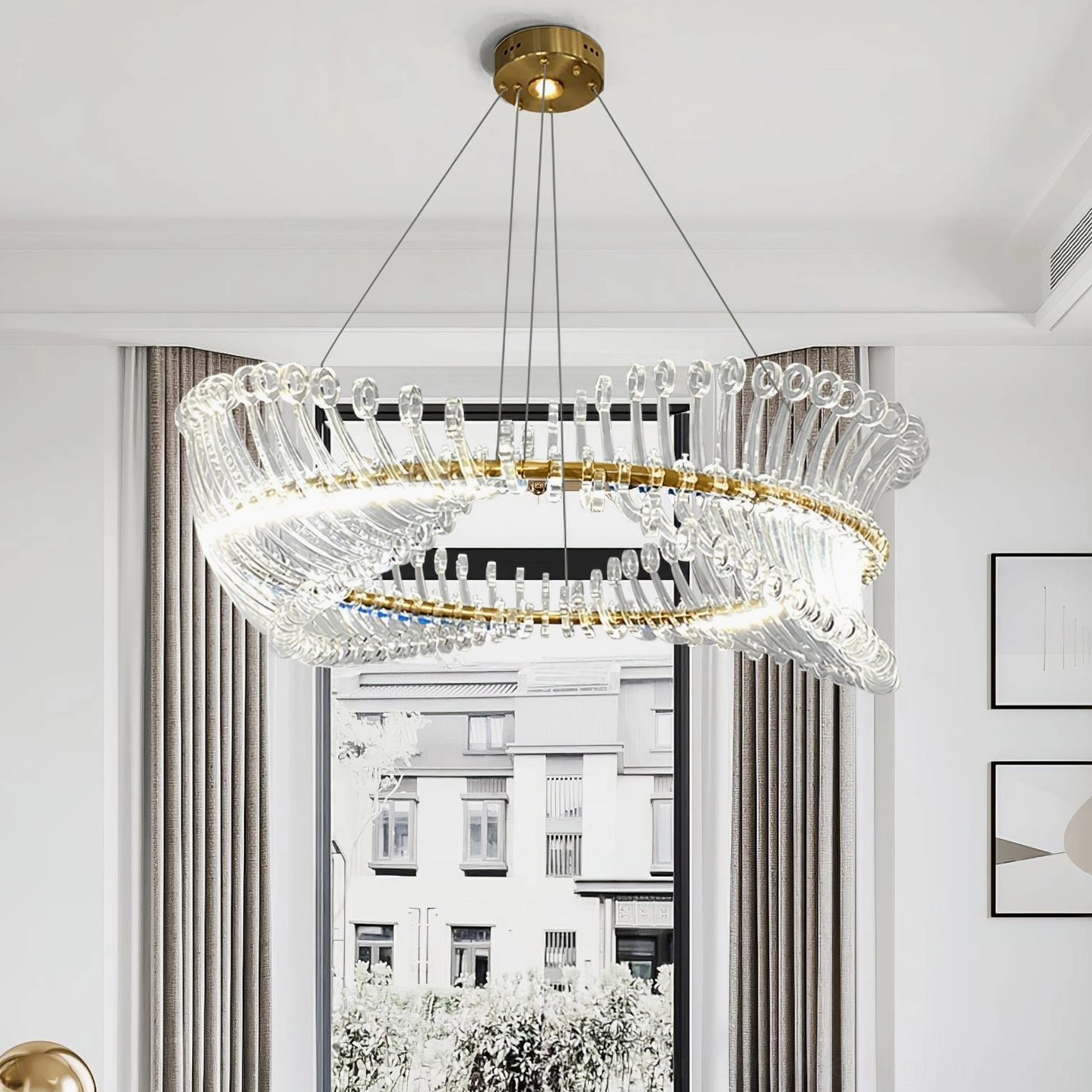 Modern gold Möbius chandelier low-angle view in living room with floor-to-ceiling windows and brass hardware