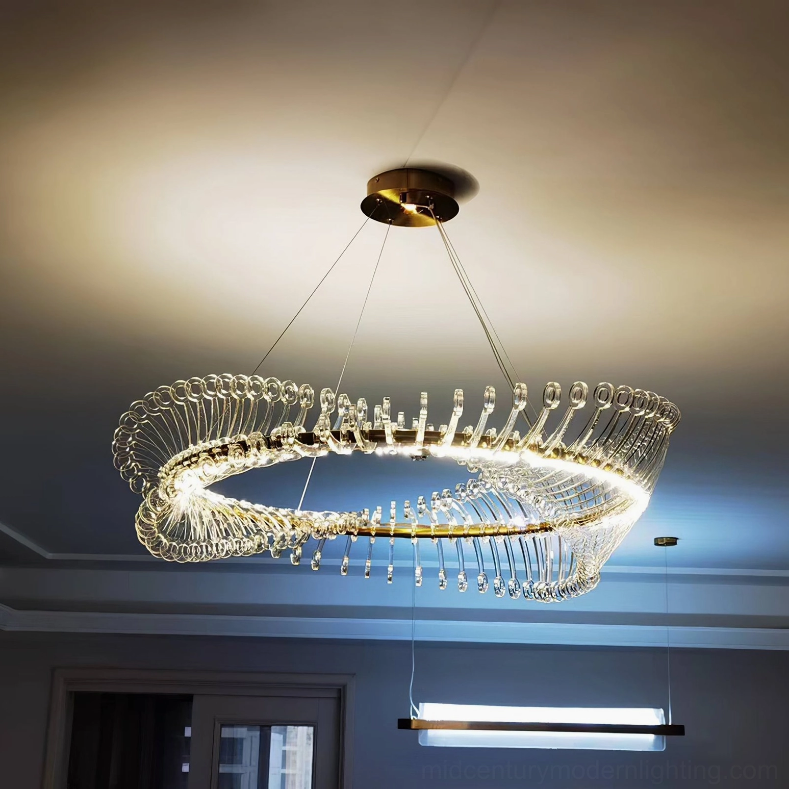 Modern Möbius strip gold chandelier showing twisted loop silhouette and transparency with studio lighting