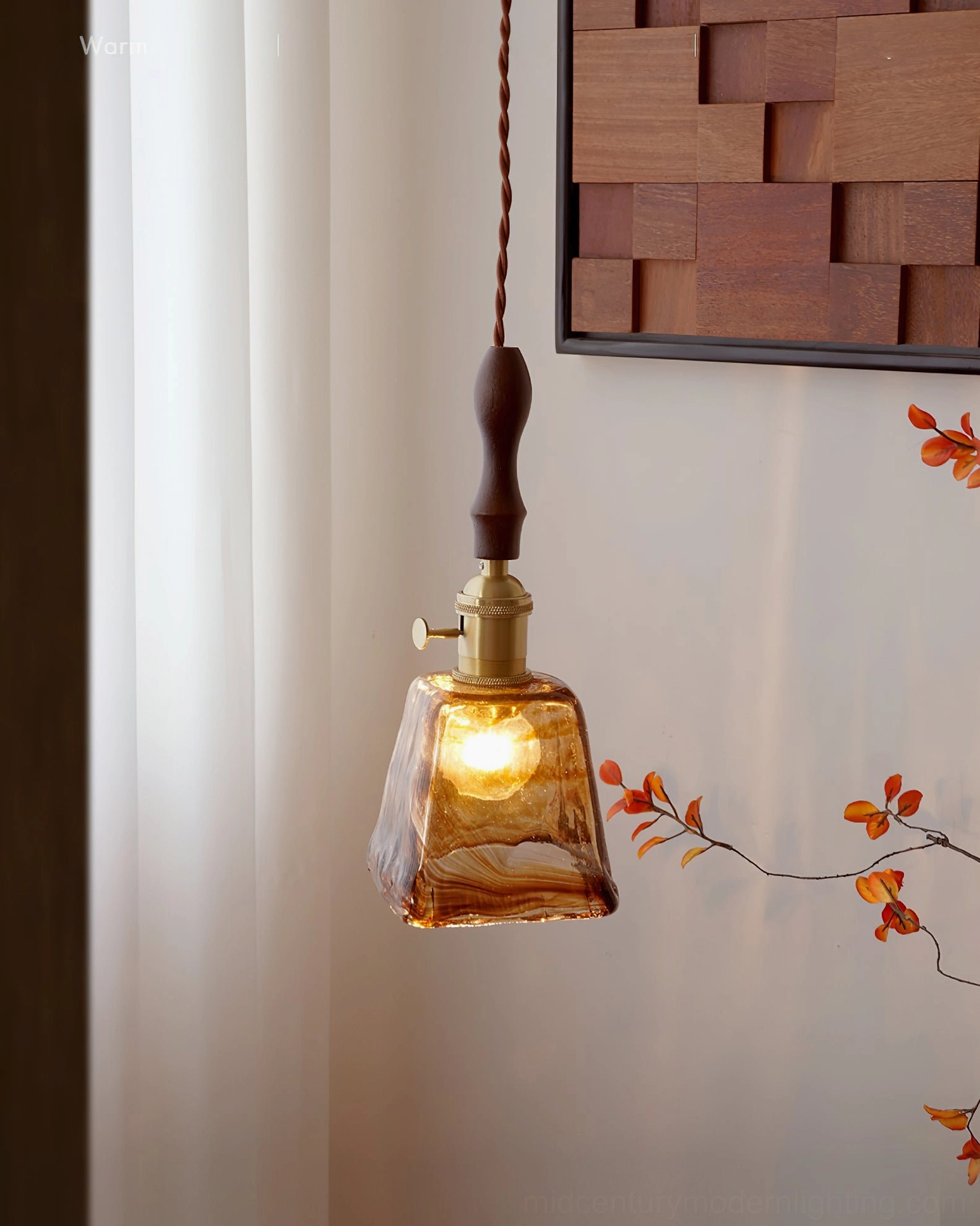 Contemporary amber glass pendant lamp with brass fixture mounted above interior space, warm ambient lighting effect