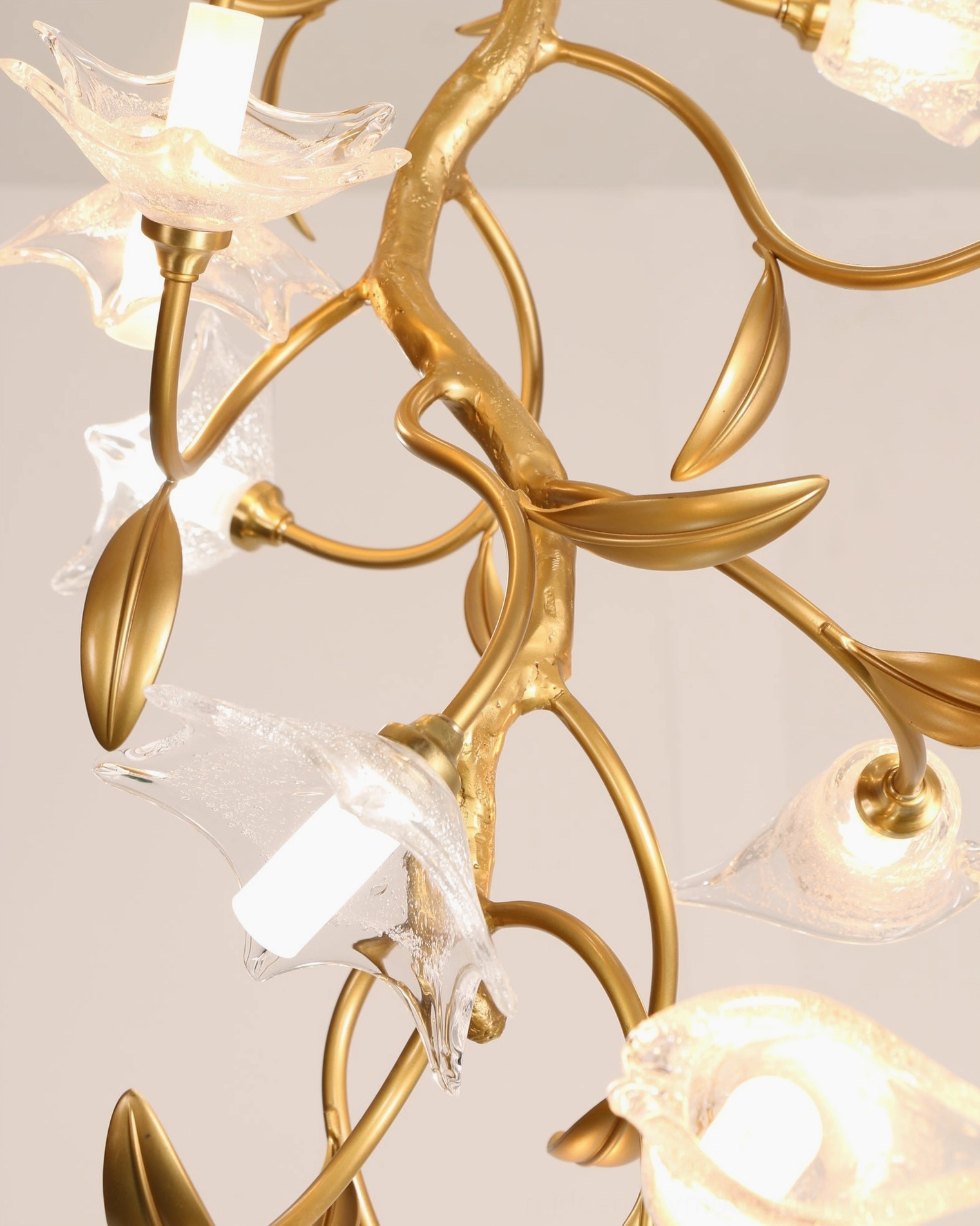 Modern botanical chandelier ceiling fixture showing delicate glass petals and branching brass structure