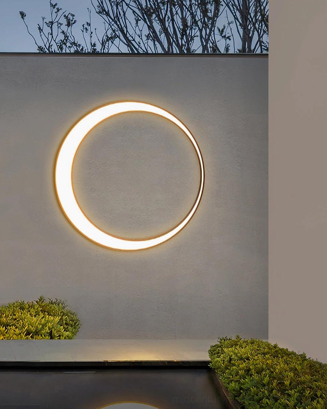 Large single circular LED outdoor wall lamp close-up with warm LED glow on small modern courtyard facade