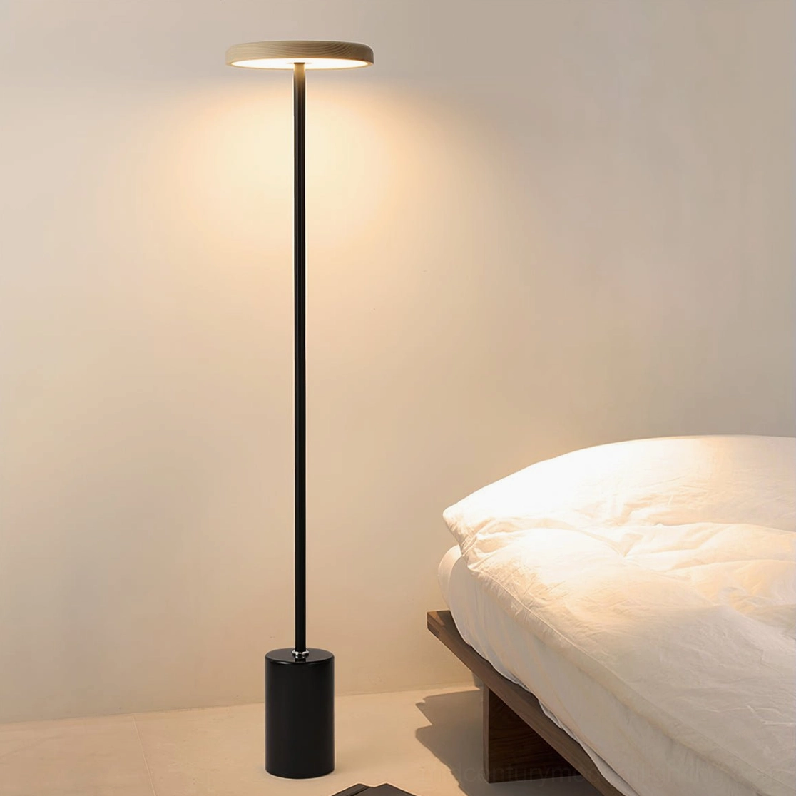 Minimalist black floor lamp beside low platform bed in modern bedroom, soft ambient warm lighting, mid-century modern interior design