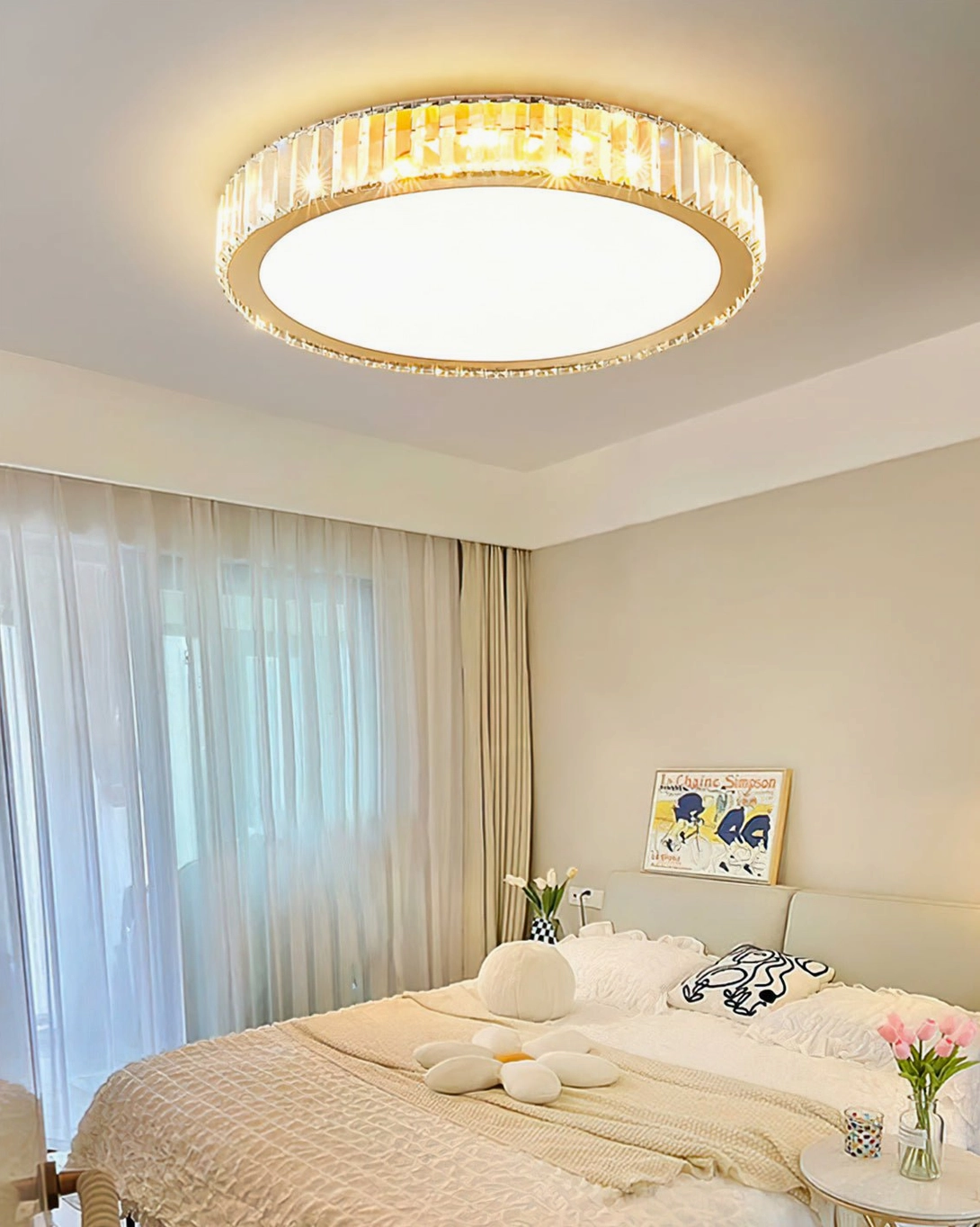 Round gold crystal ceiling fixture installed in cozy bedroom with side table flowers