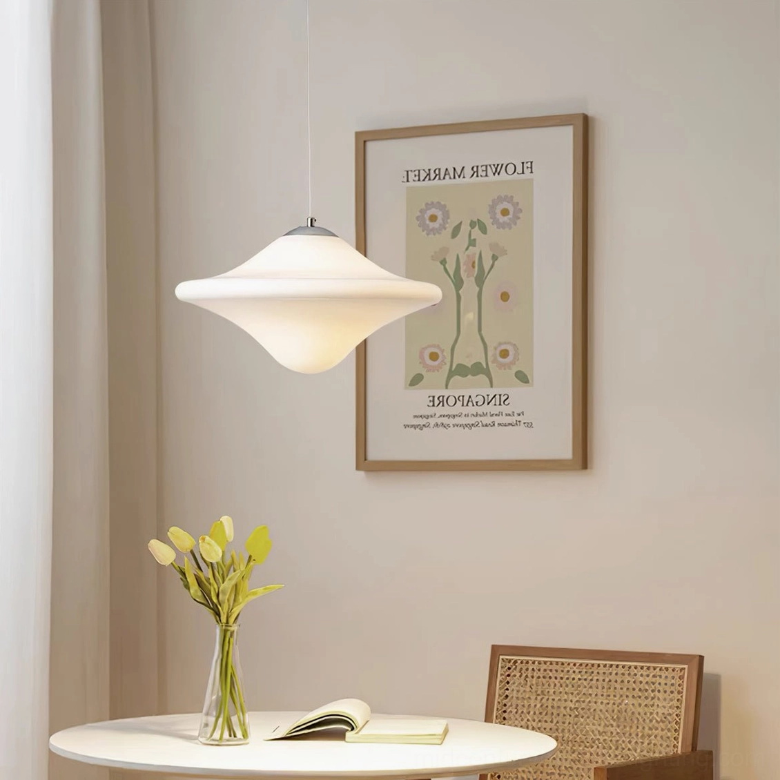 Modern pendant lamp suspended in minimalist dining nook with warm neutral lighting and wall art