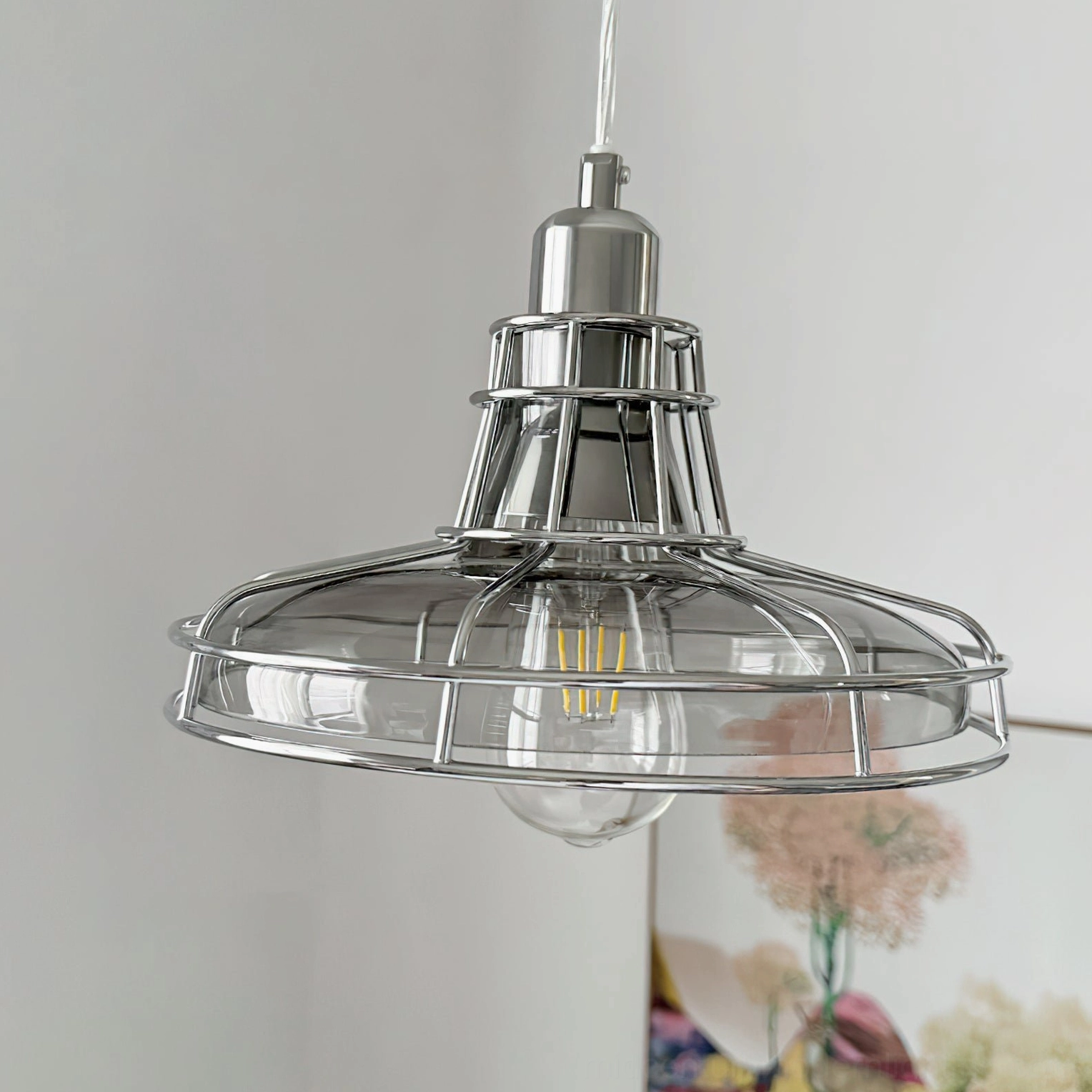 Mid-century modern pendant light with multi-tiered metal fitting and clear glass shade, close-up frontal view