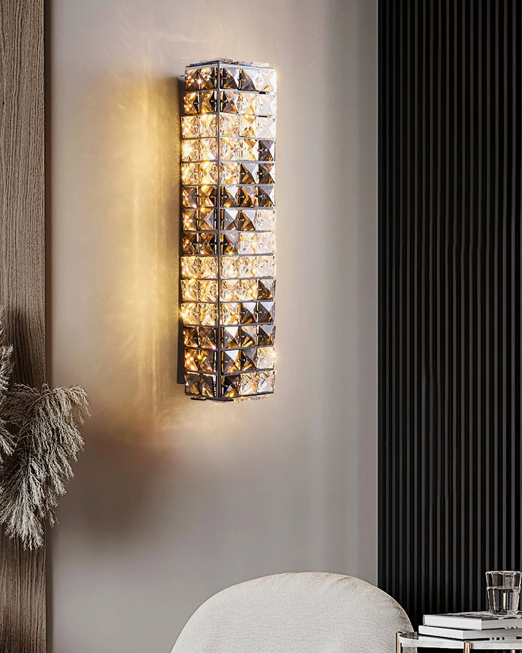 Contemporary crystal sconce illuminating living room with dark wood paneling and dried plant styling