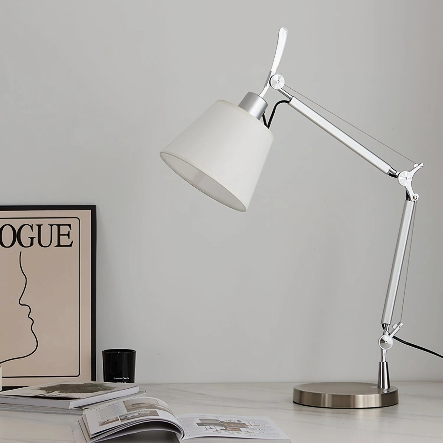 Contemporary adjustable lamp styled in home office setting with magazines and decorative candle on desk