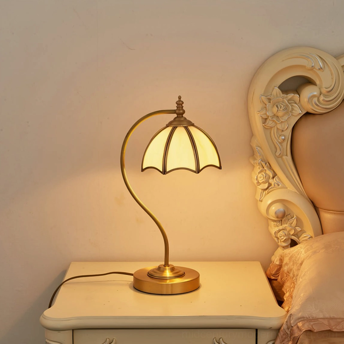 Modern umbrella table lamp illuminating European-style bedroom with carved wooden headboard