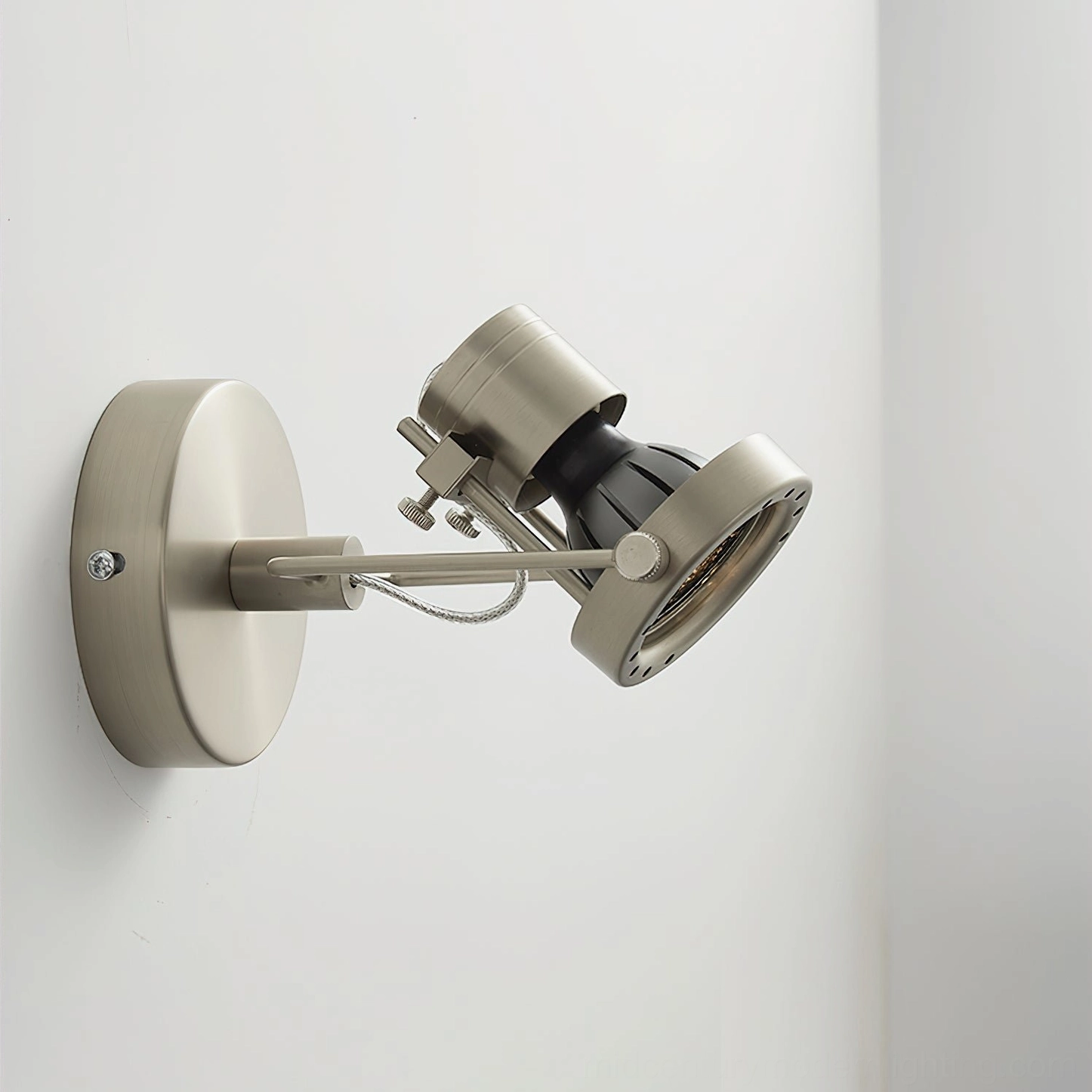Industrial wall mounting light in corner interior setting with unlit brushed nickel arm and simple metal design