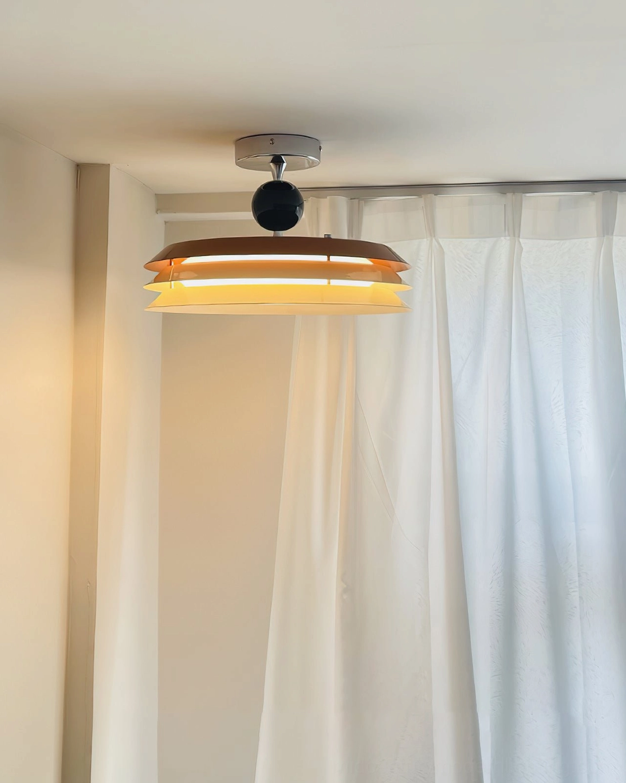 Light wood-tone semi-flush ceiling lamp with dual-layer design in room with sheer white curtains and natural daylight