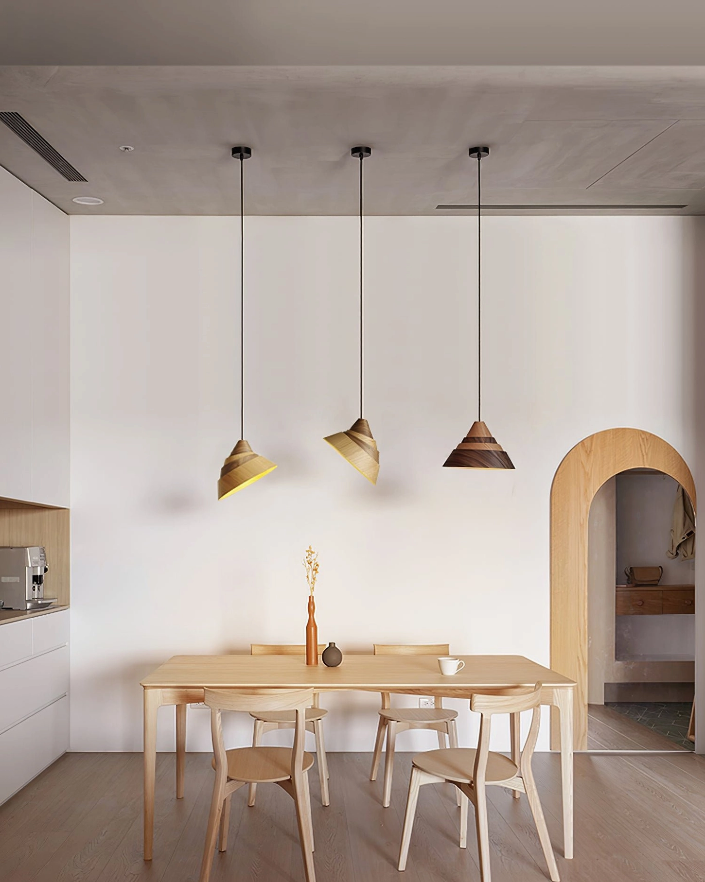 Set of tapered wooden pendant lights suspended in Nordic-style kitchen, warm brown ash and walnut finish with coordinated fixtures